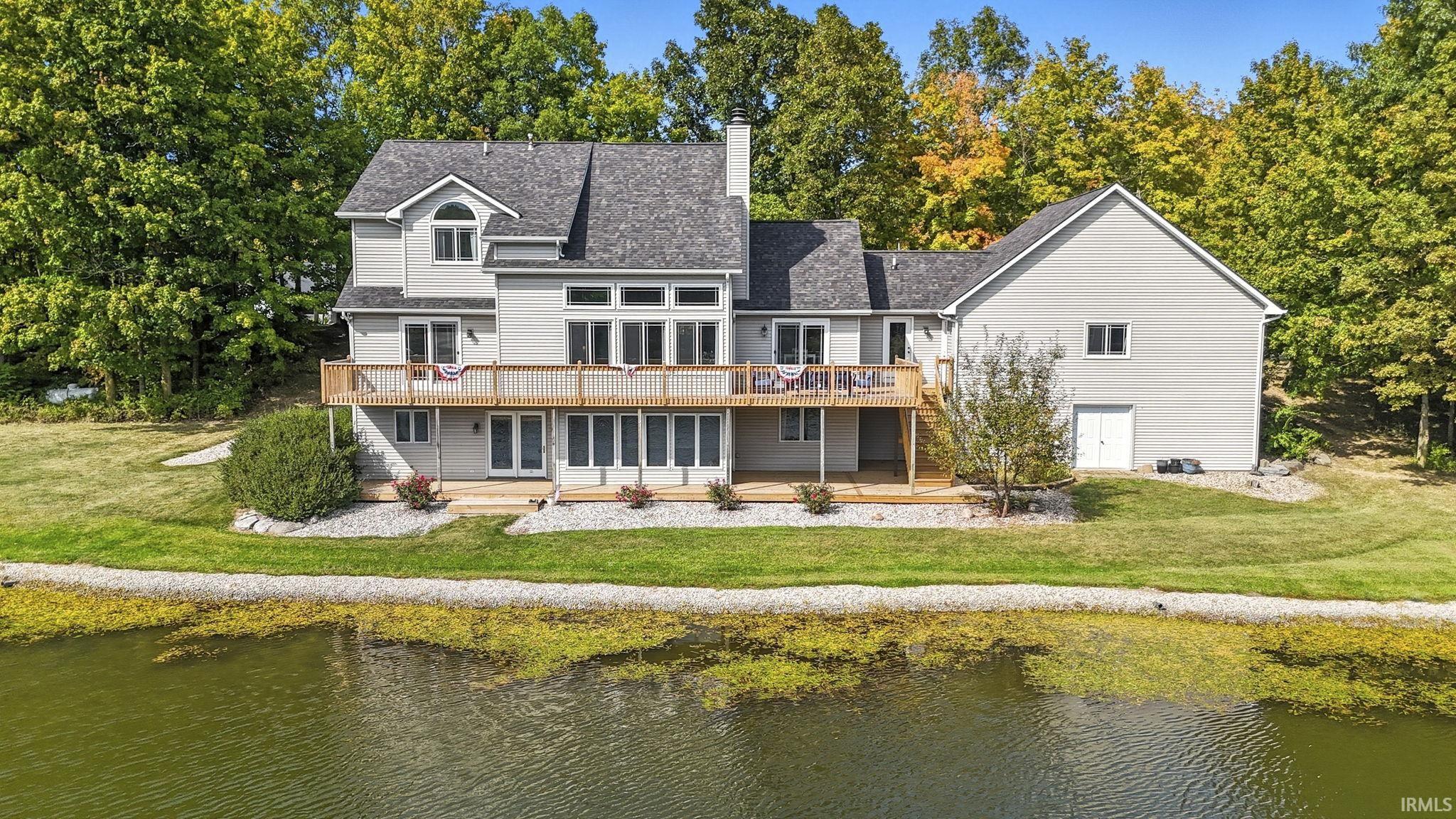 Rear view of property featuring a lawn, a deck with water view, and a chimney
