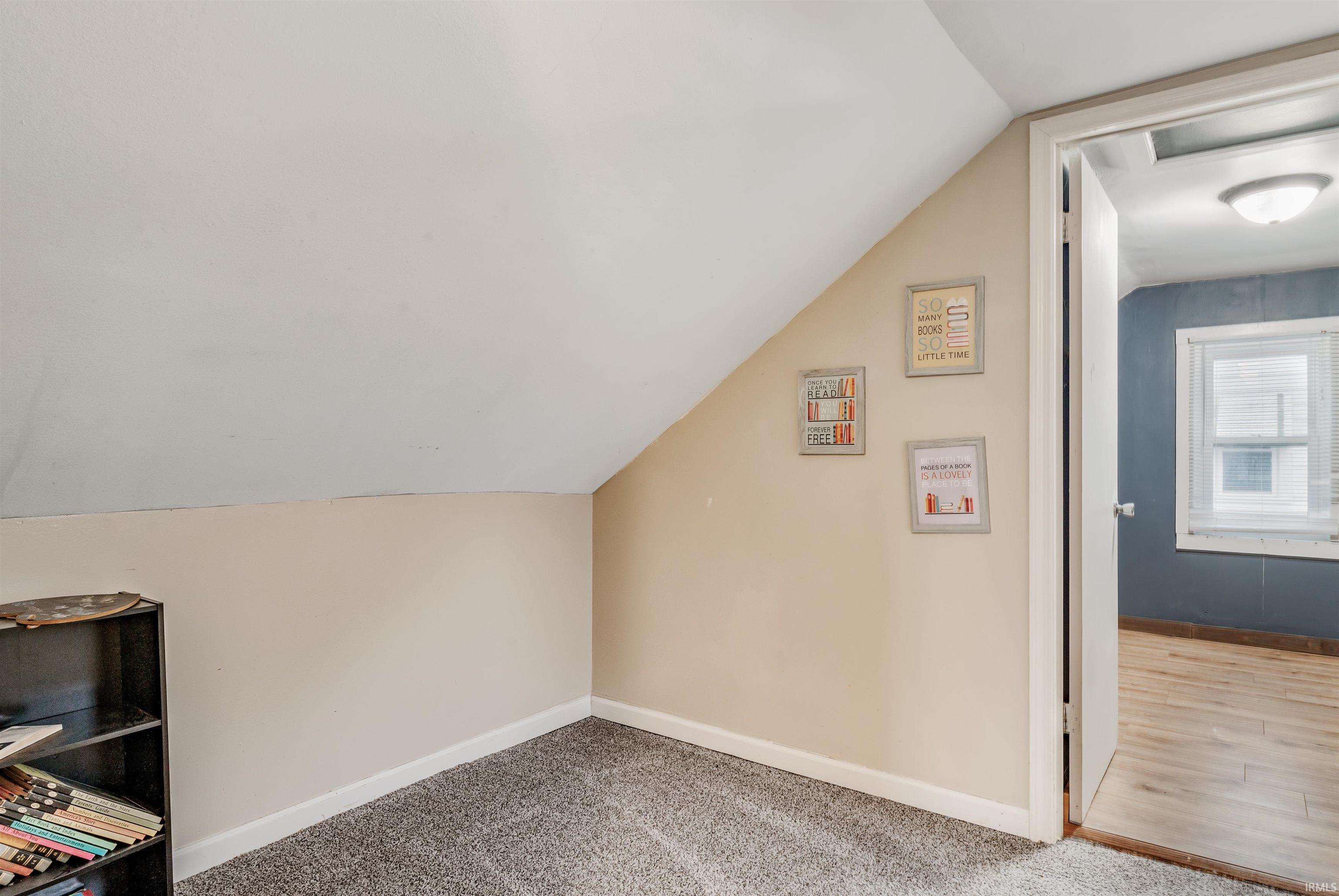 Additional living space featuring vaulted ceiling and carpet