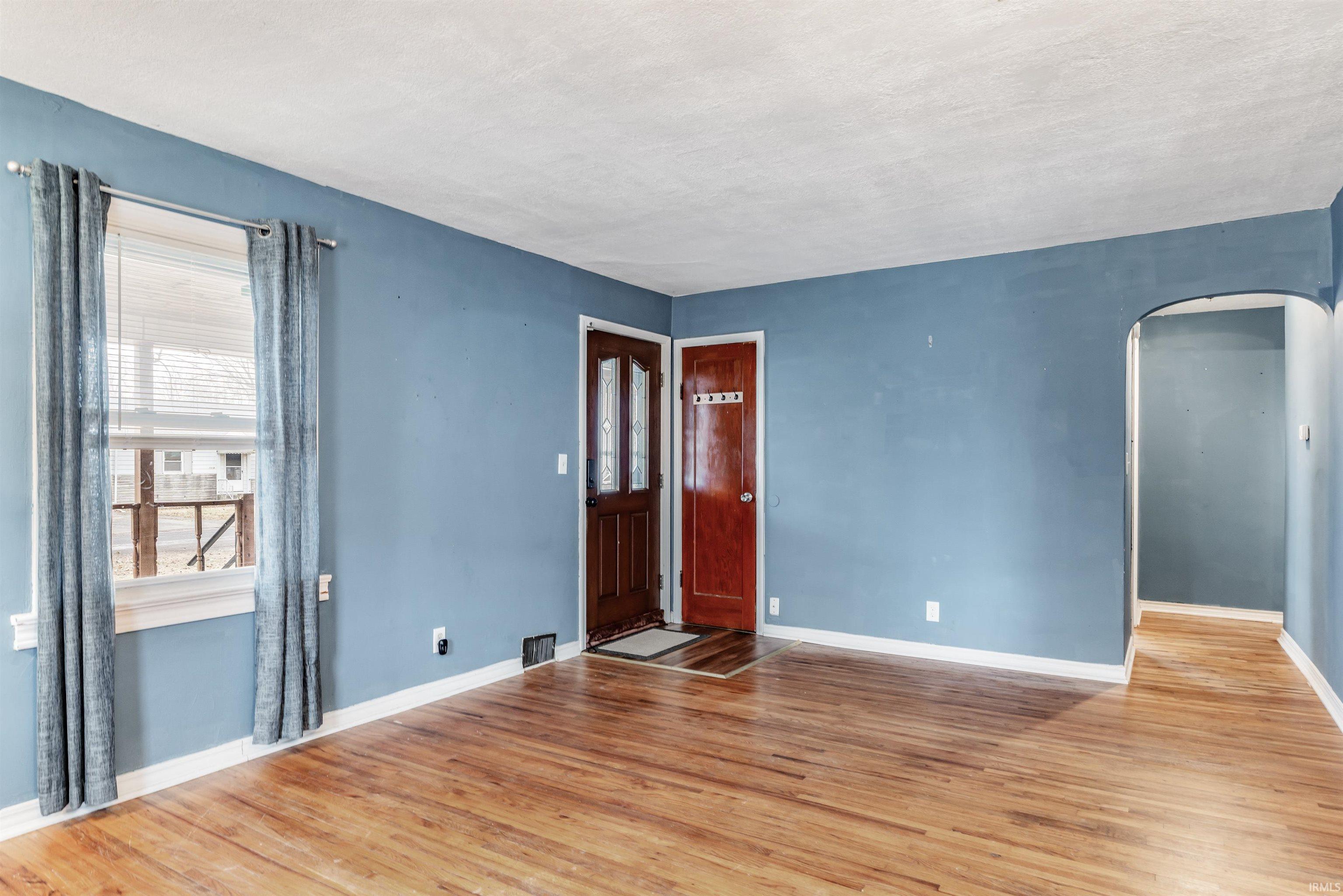 Foyer entrance with arched walkways and light wood-style flooring