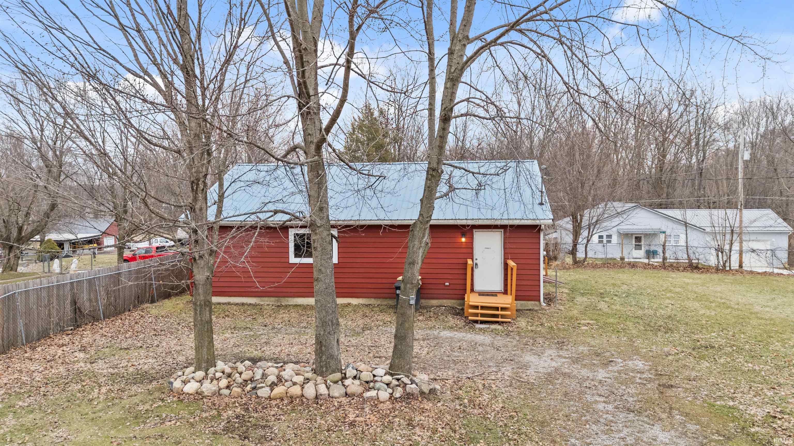 View of home's exterior with a fenced backyard, entry steps, and a metal roof