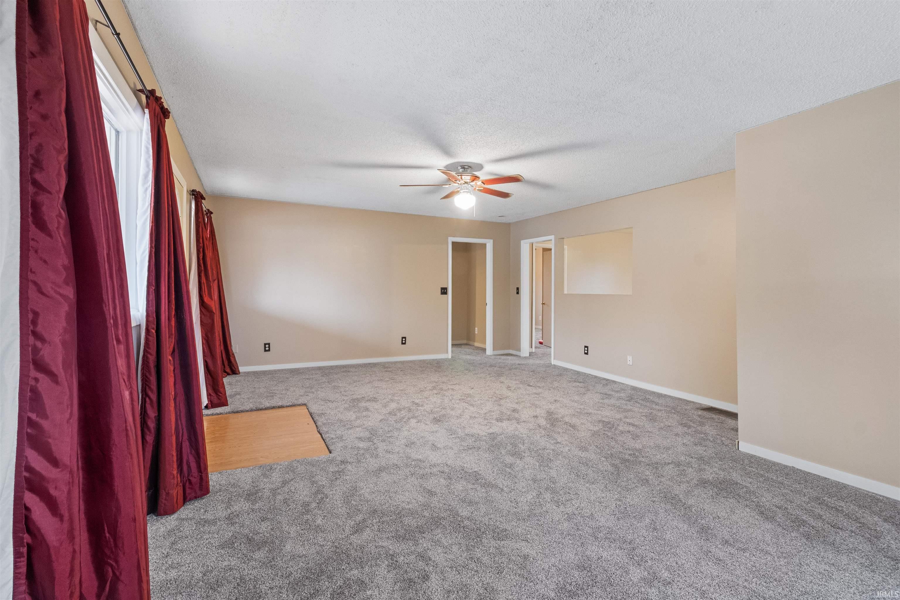 Carpeted spare room with a ceiling fan and a textured ceiling