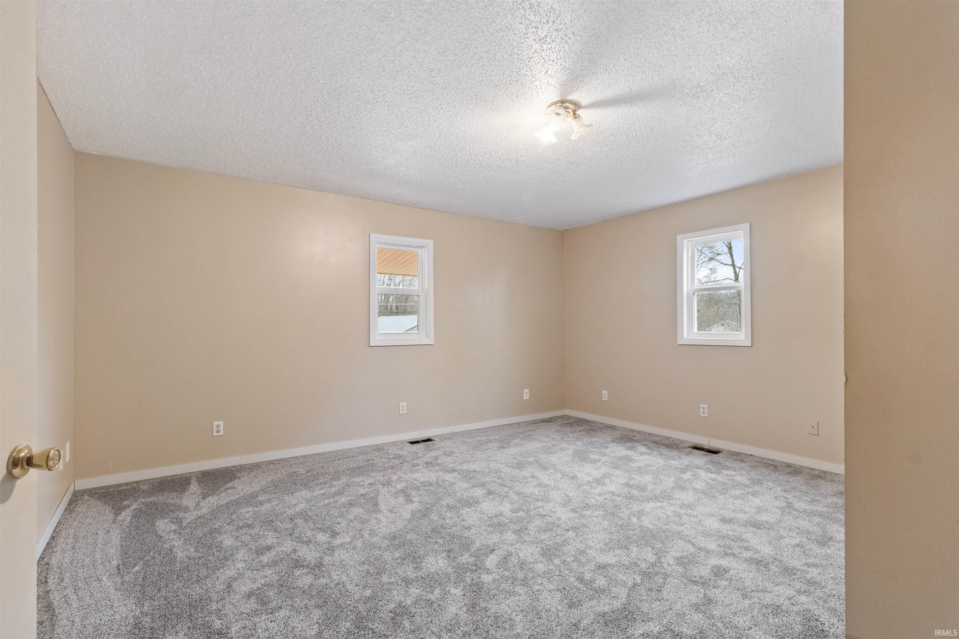 Empty room with a textured ceiling and carpet flooring
