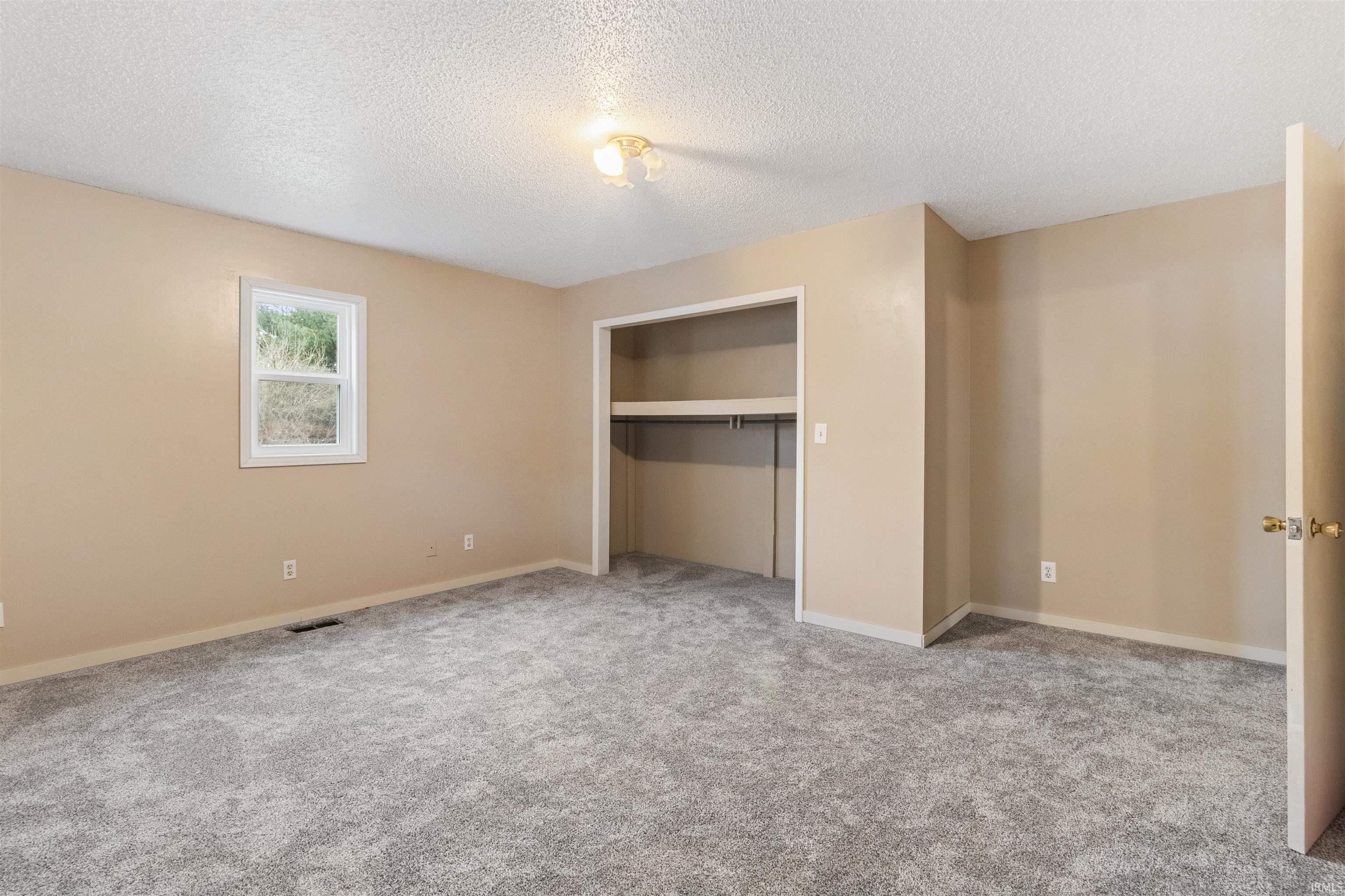 Unfurnished bedroom with a closet, light colored carpet, and a textured ceiling