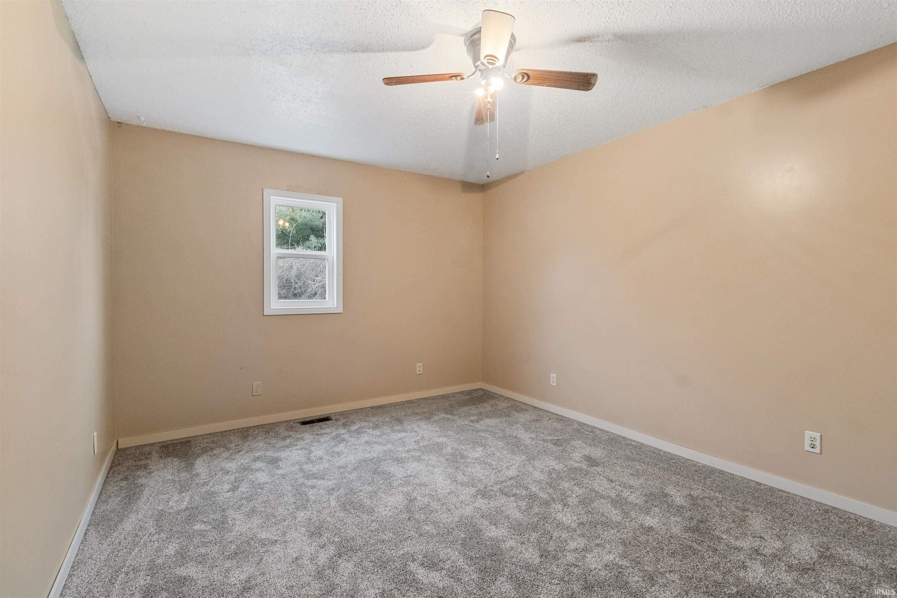 Unfurnished room featuring carpet, a textured ceiling, and ceiling fan