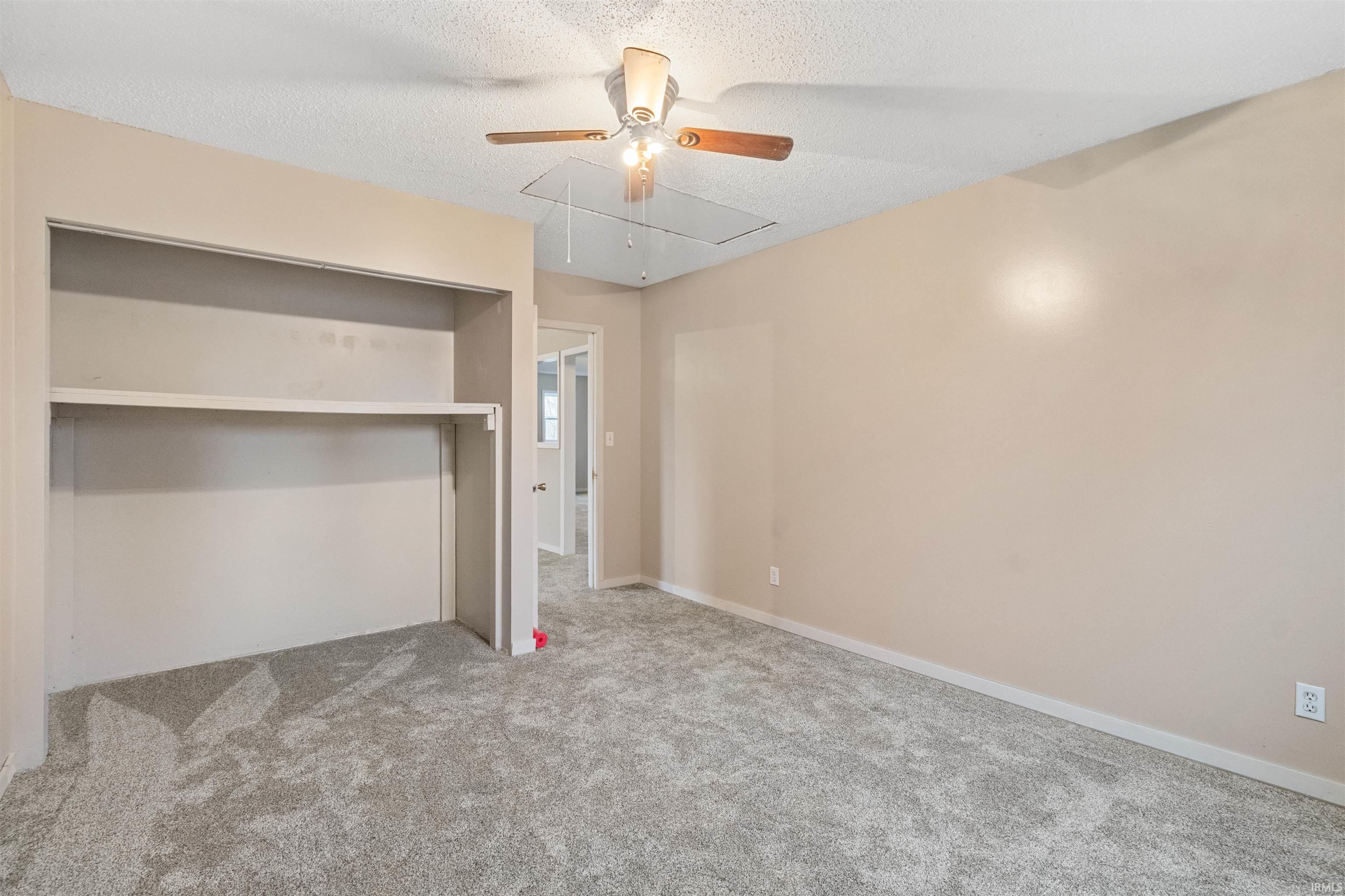 Unfurnished bedroom with a textured ceiling, light colored carpet, a closet, and ceiling fan