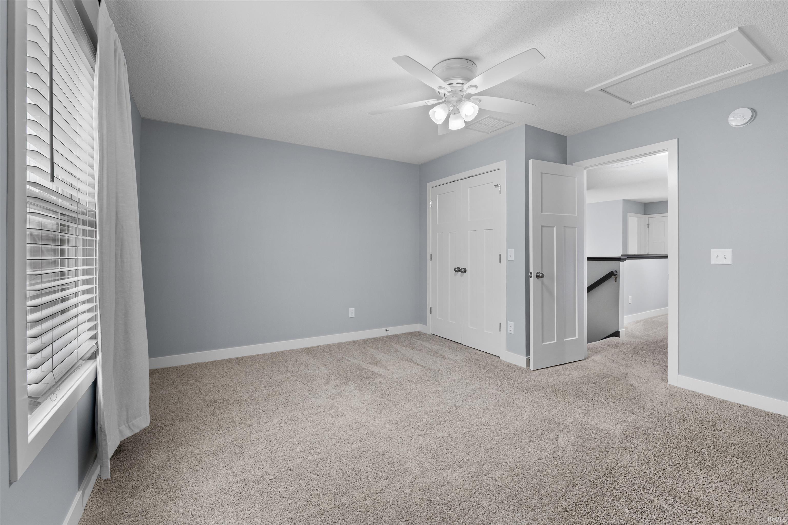 Bedroom featuring light carpet, a ceiling fan, a closet, and a textured ceiling