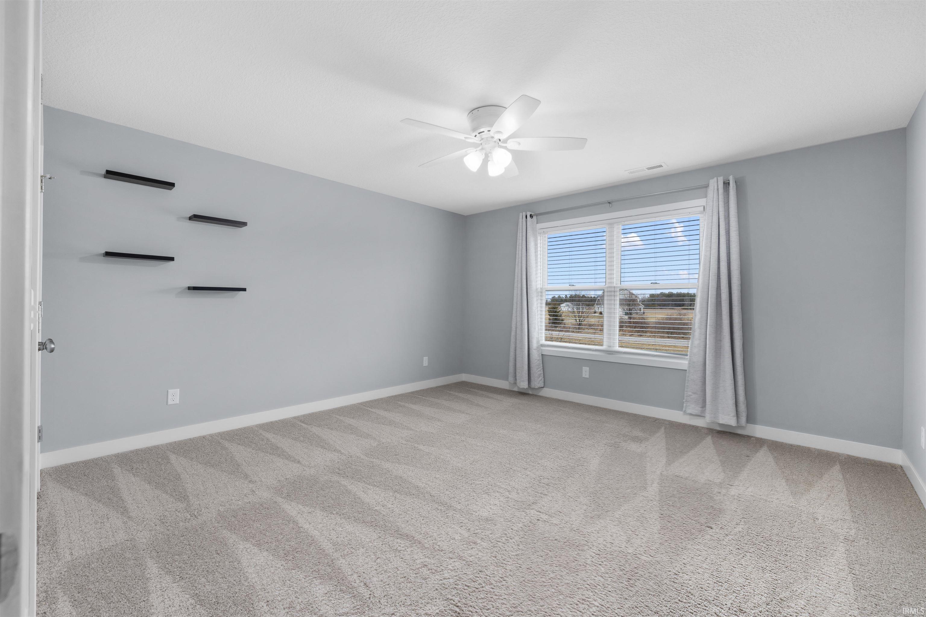 Bedroom with light colored carpet and a ceiling fan