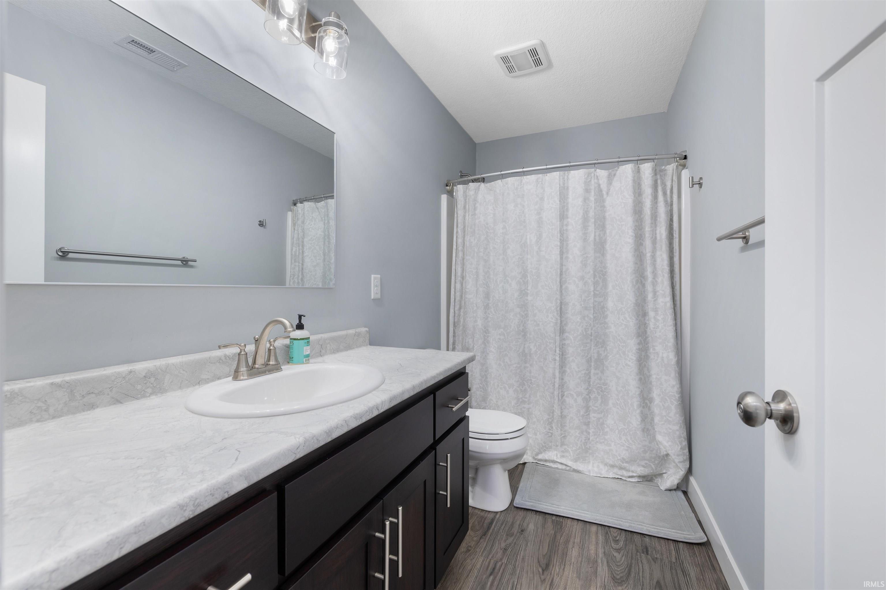 Bathroom featuring vanity, a shower with curtain, and dark wood-type flooring