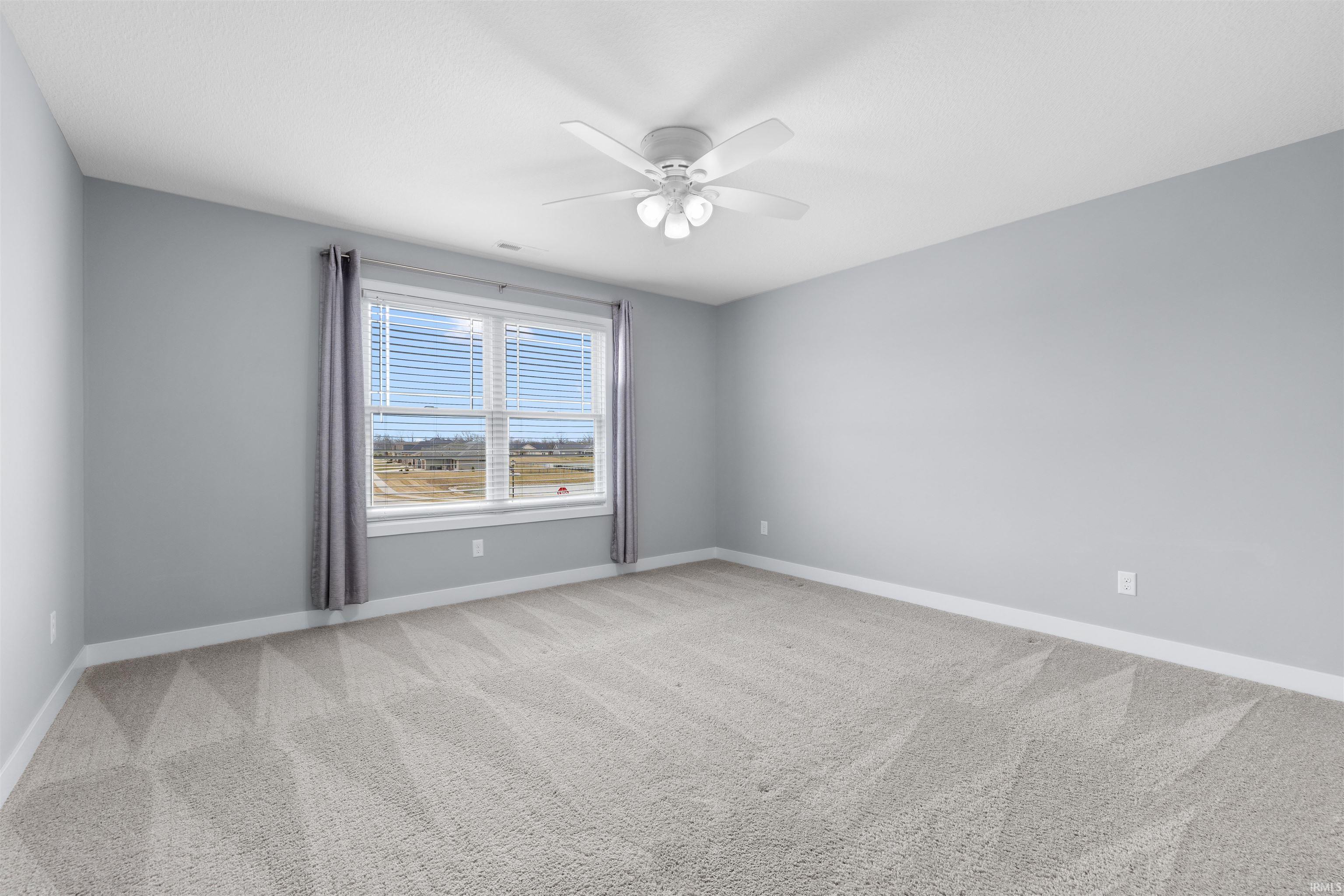 Bedroom with light colored carpet and a ceiling fan