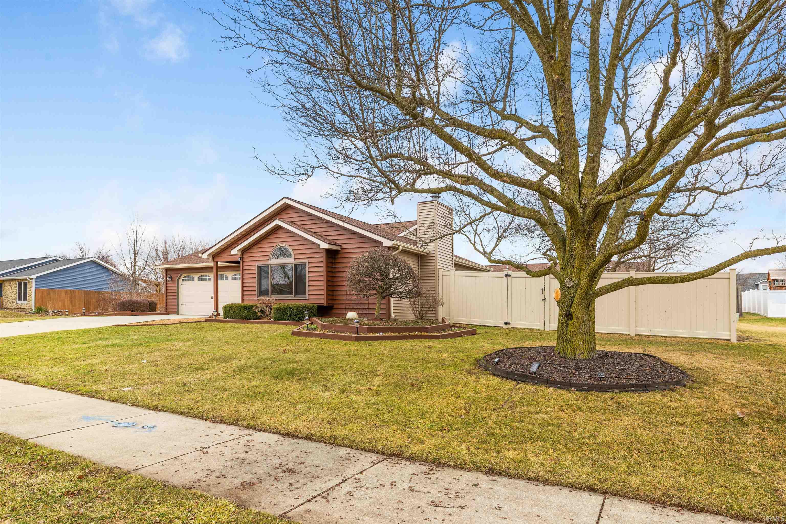 Ranch-style home featuring a gate, a chimney, concrete driveway, and an attached garage