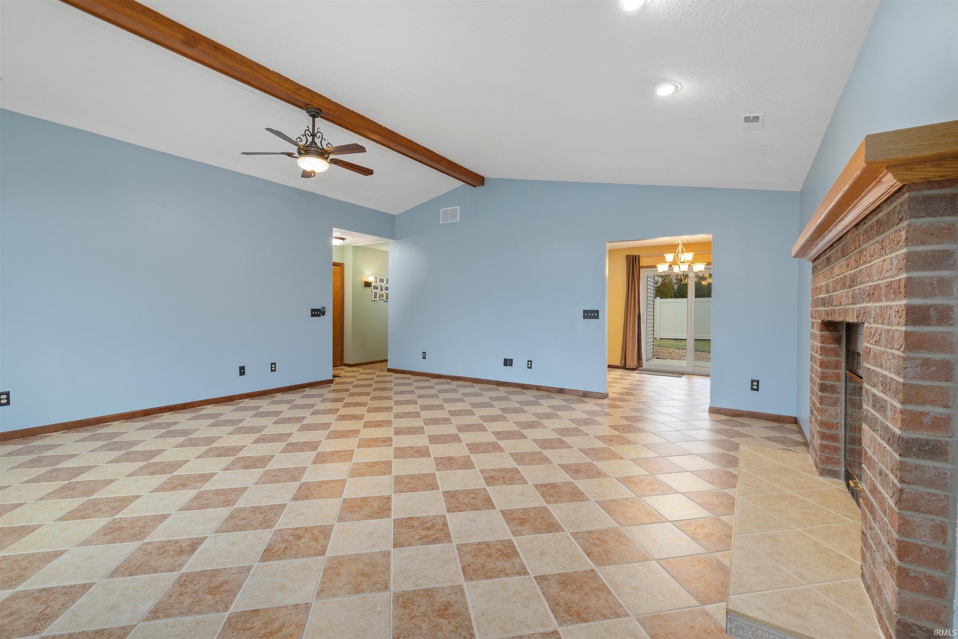 Unfurnished living room with hanging lights, ceiling fan, a fireplace, and beamed ceiling