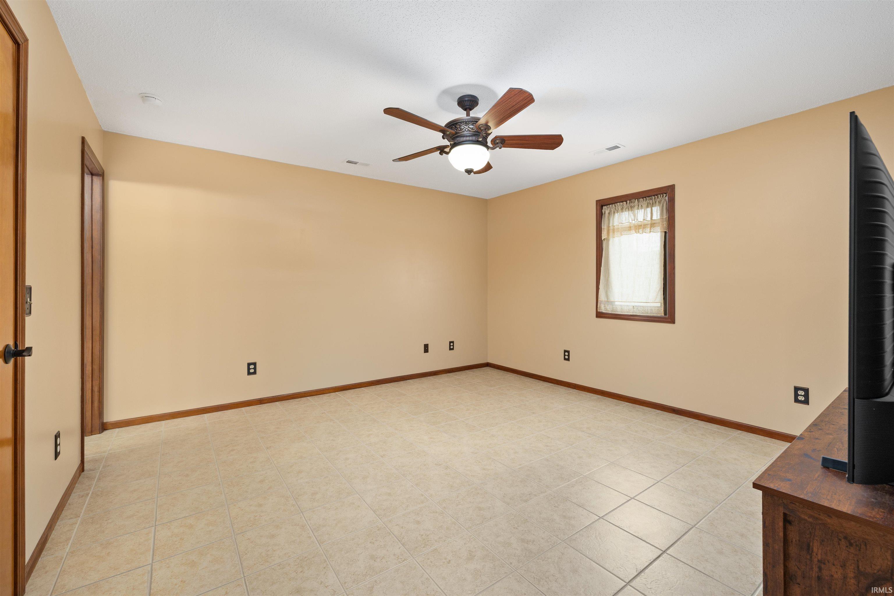Empty room with a ceiling fan and light tile patterned floors