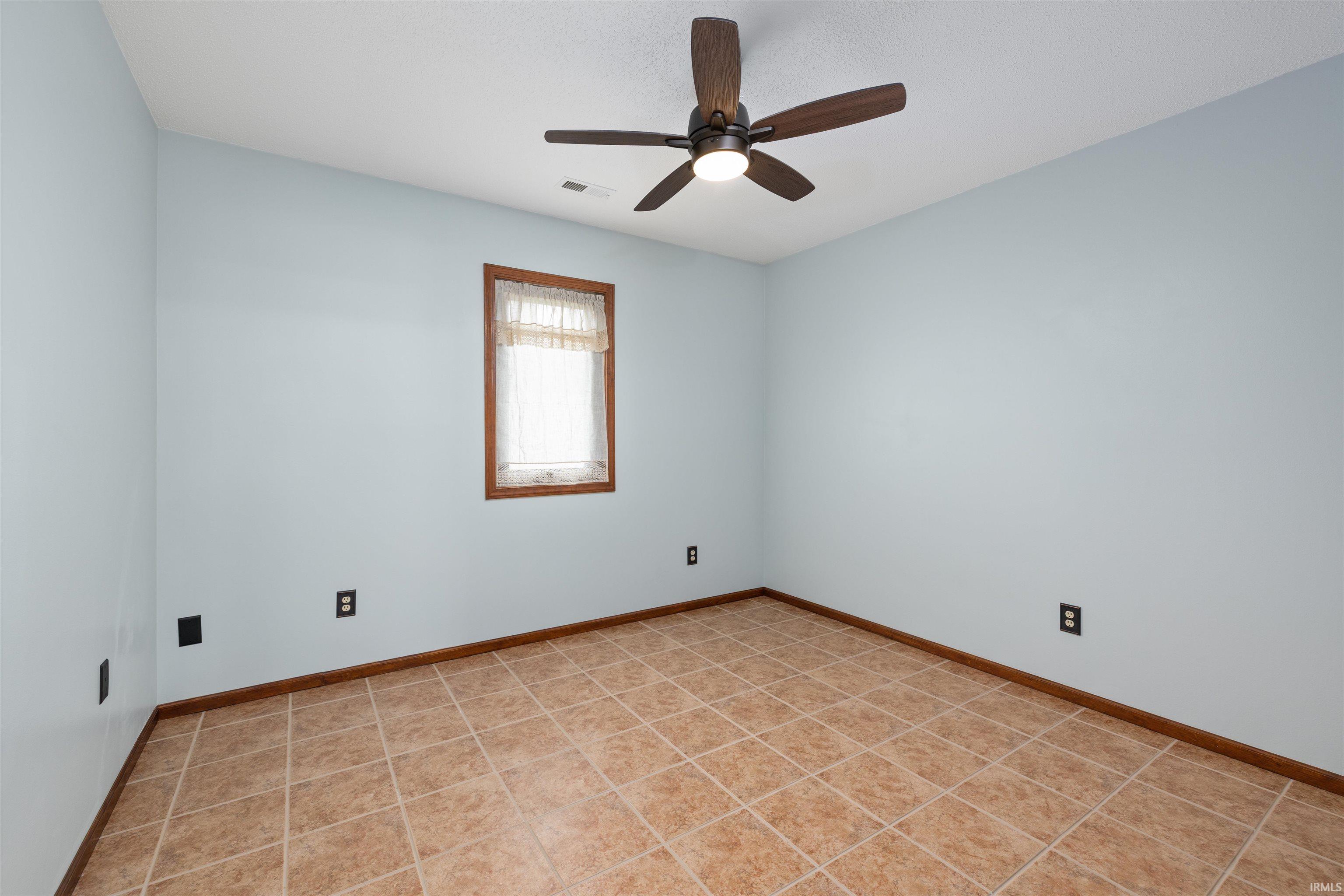 Unfurnished room featuring ceiling fan and light tile patterned flooring
