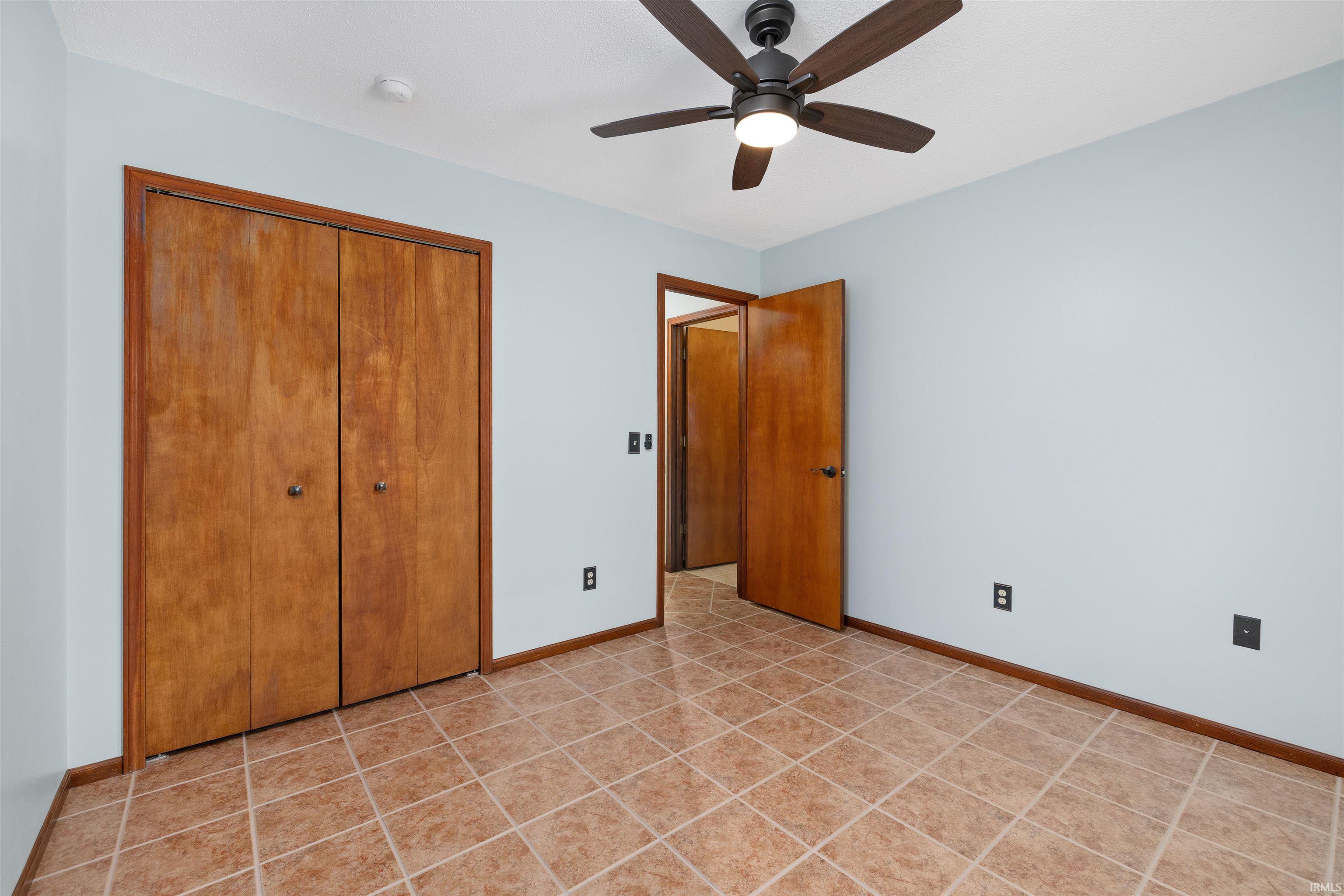 Unfurnished bedroom featuring a closet, ceiling fan, and light tile patterned floors