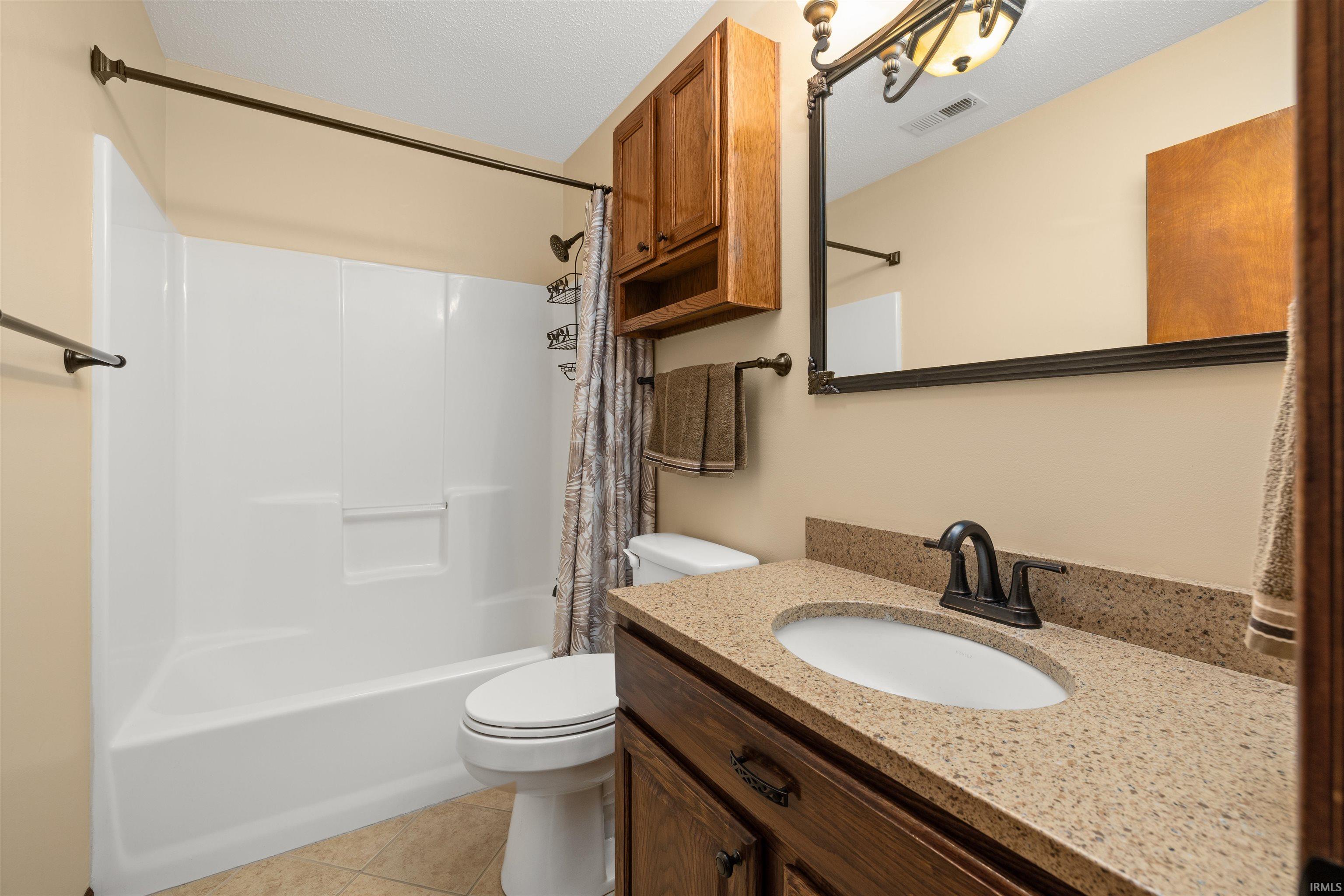 Full bathroom featuring vanity, shower / bath combo with shower curtain, and light tile patterned flooring