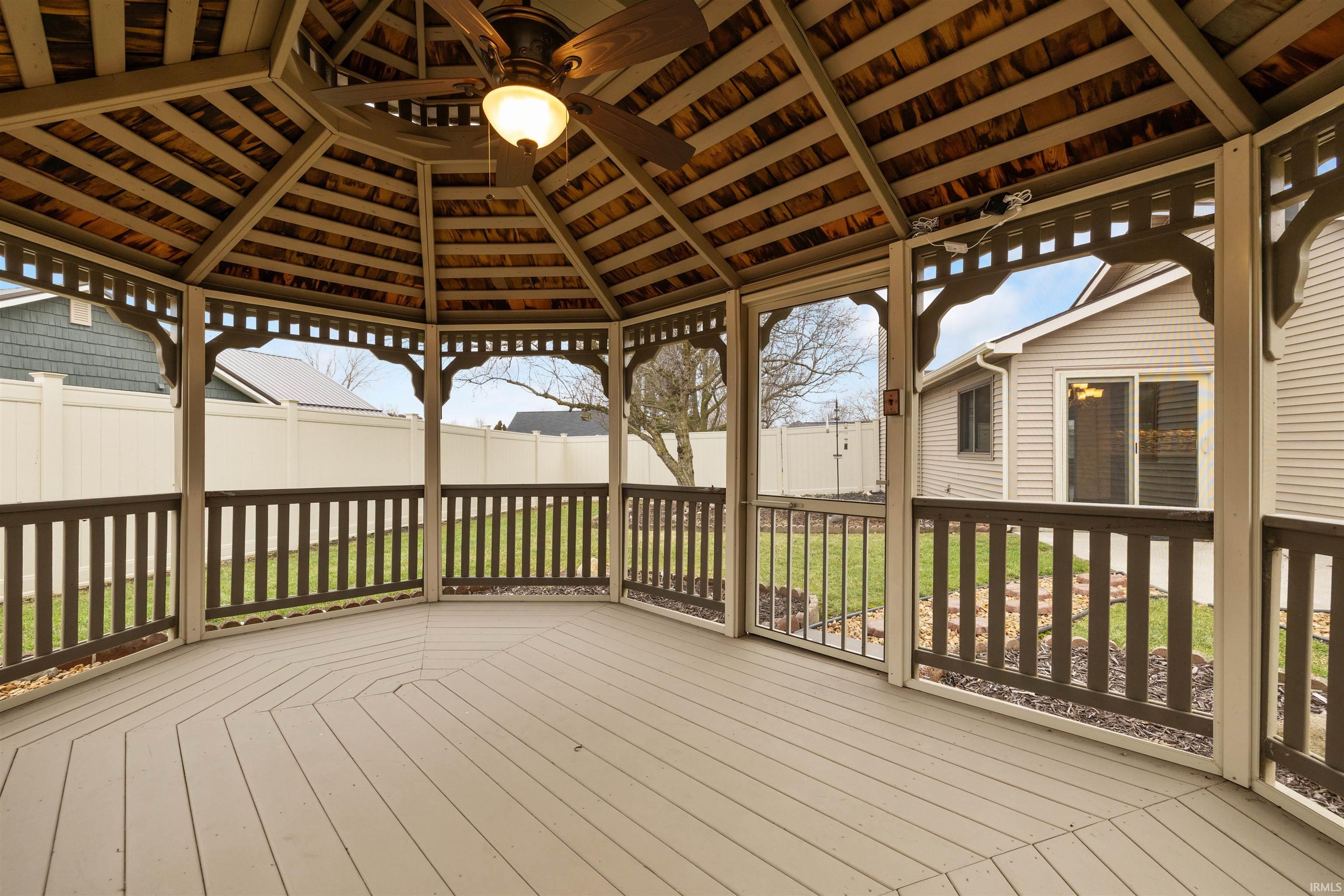 Wooden deck featuring ceiling fan, a fenced backyard, and a gazebo