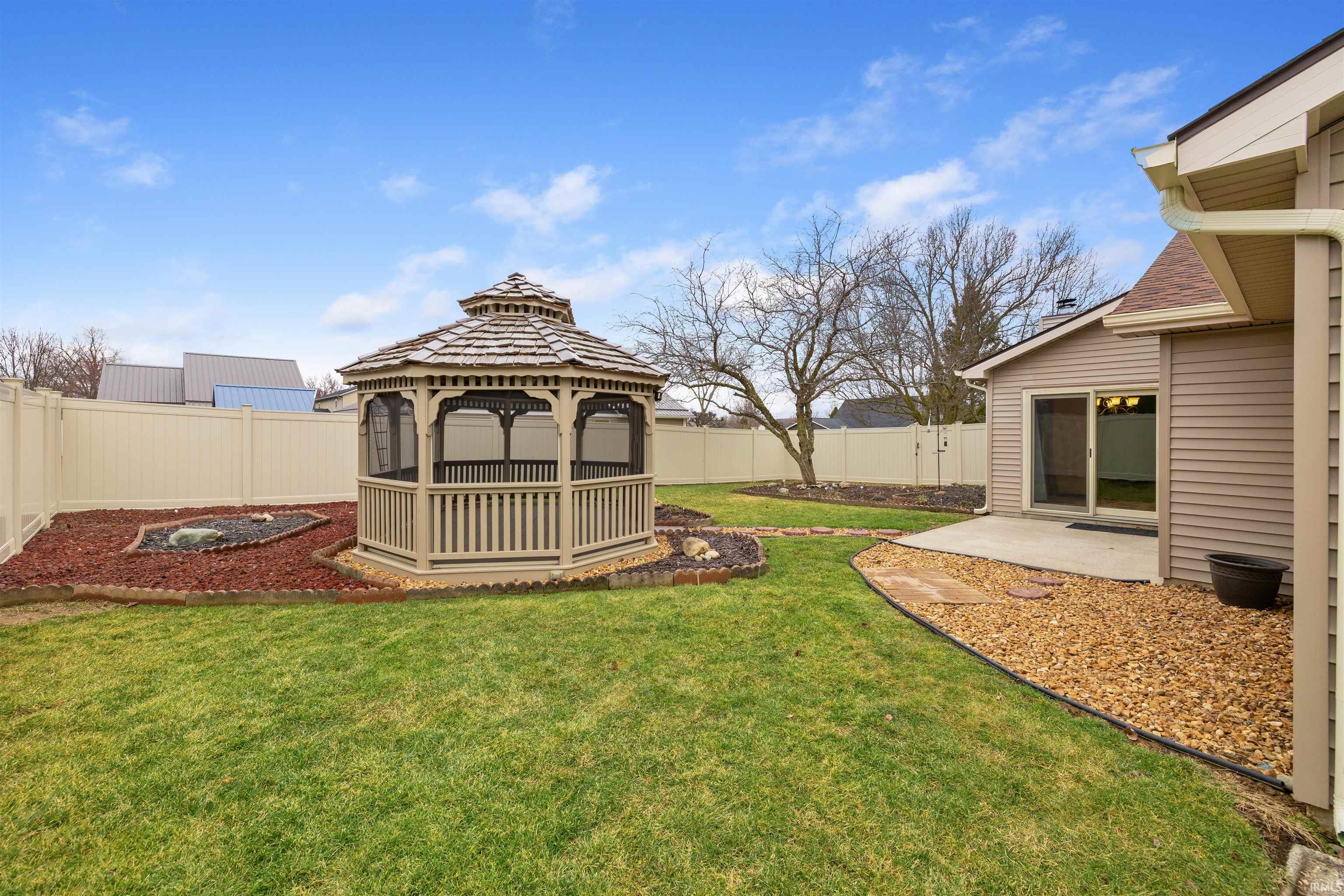 Fenced backyard featuring a patio area and a gazebo