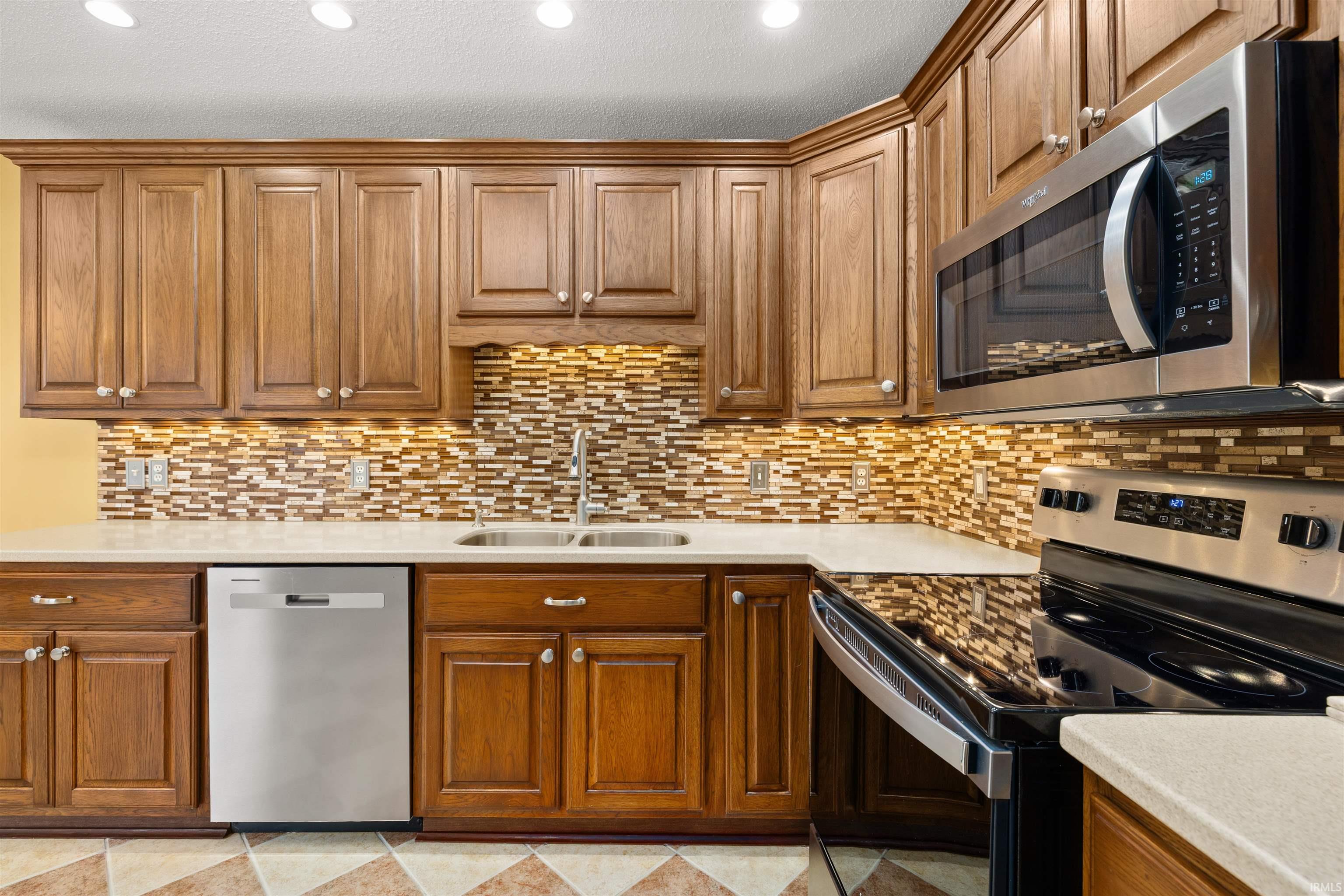 Kitchen with stainless steel appliances, wood finish cabinets, recessed lighting, and light stone counters