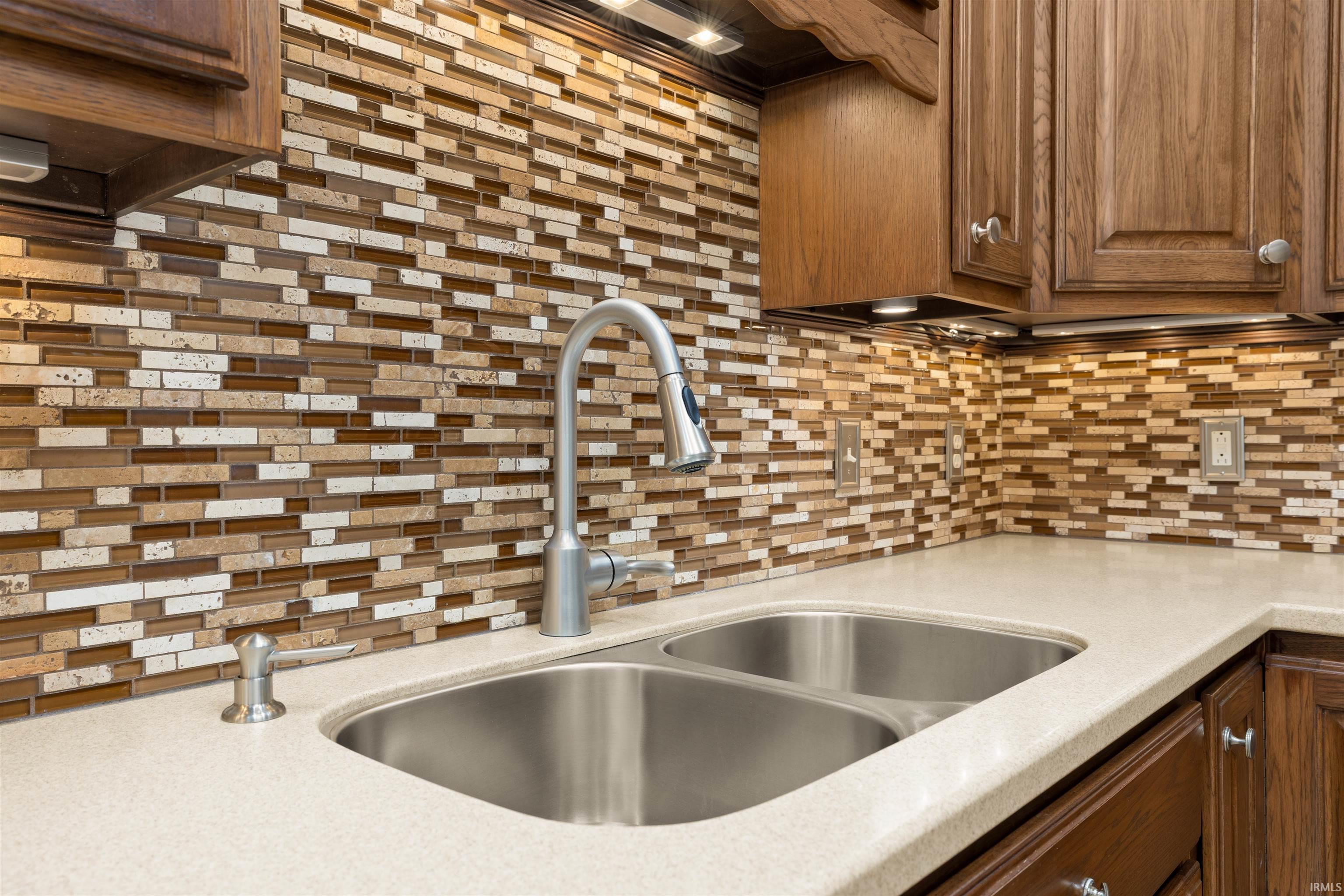 Kitchen with light stone counters, wood finish cabinetry, and backsplash