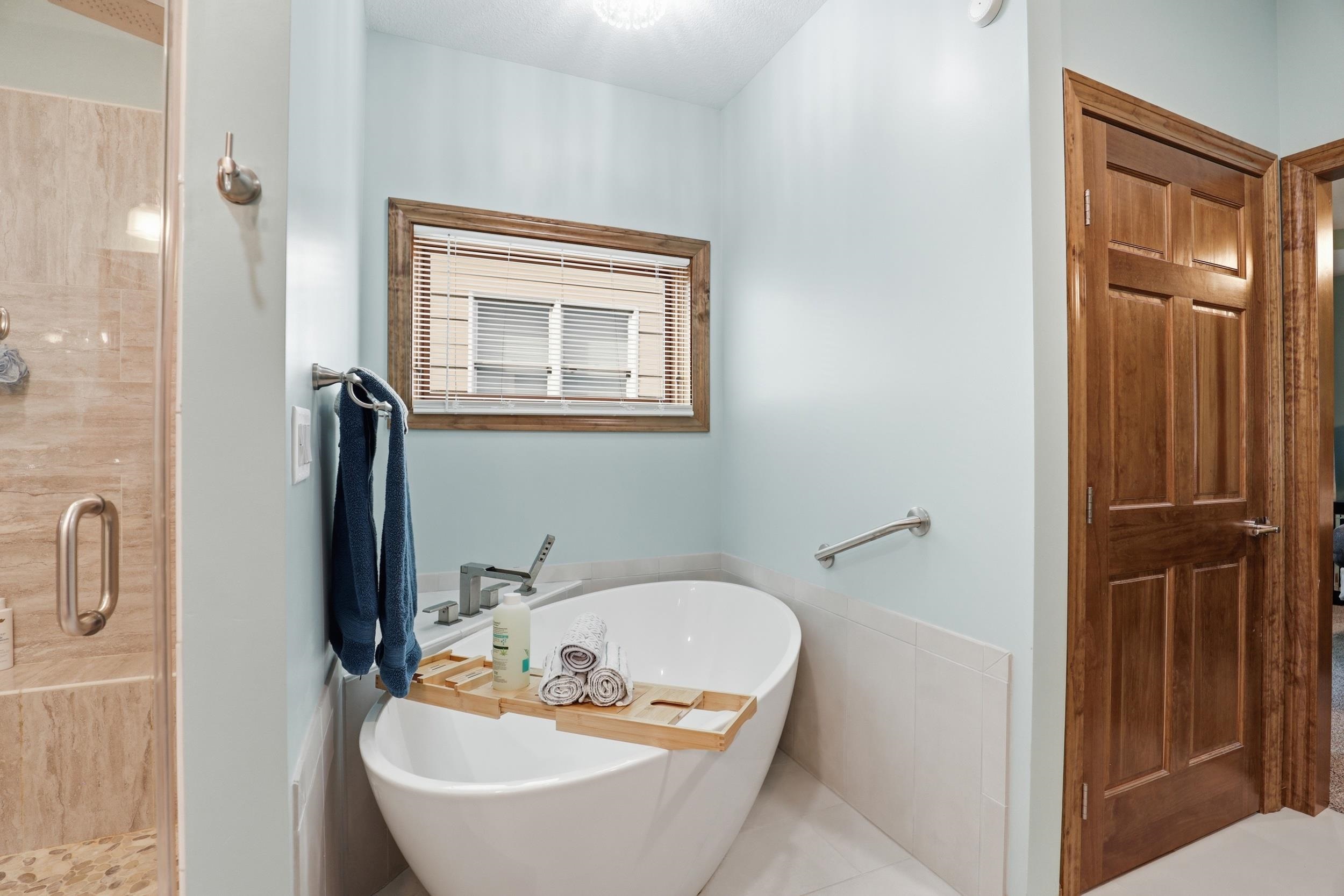 Bathroom with a freestanding bath, a stall shower, and light tile patterned floors