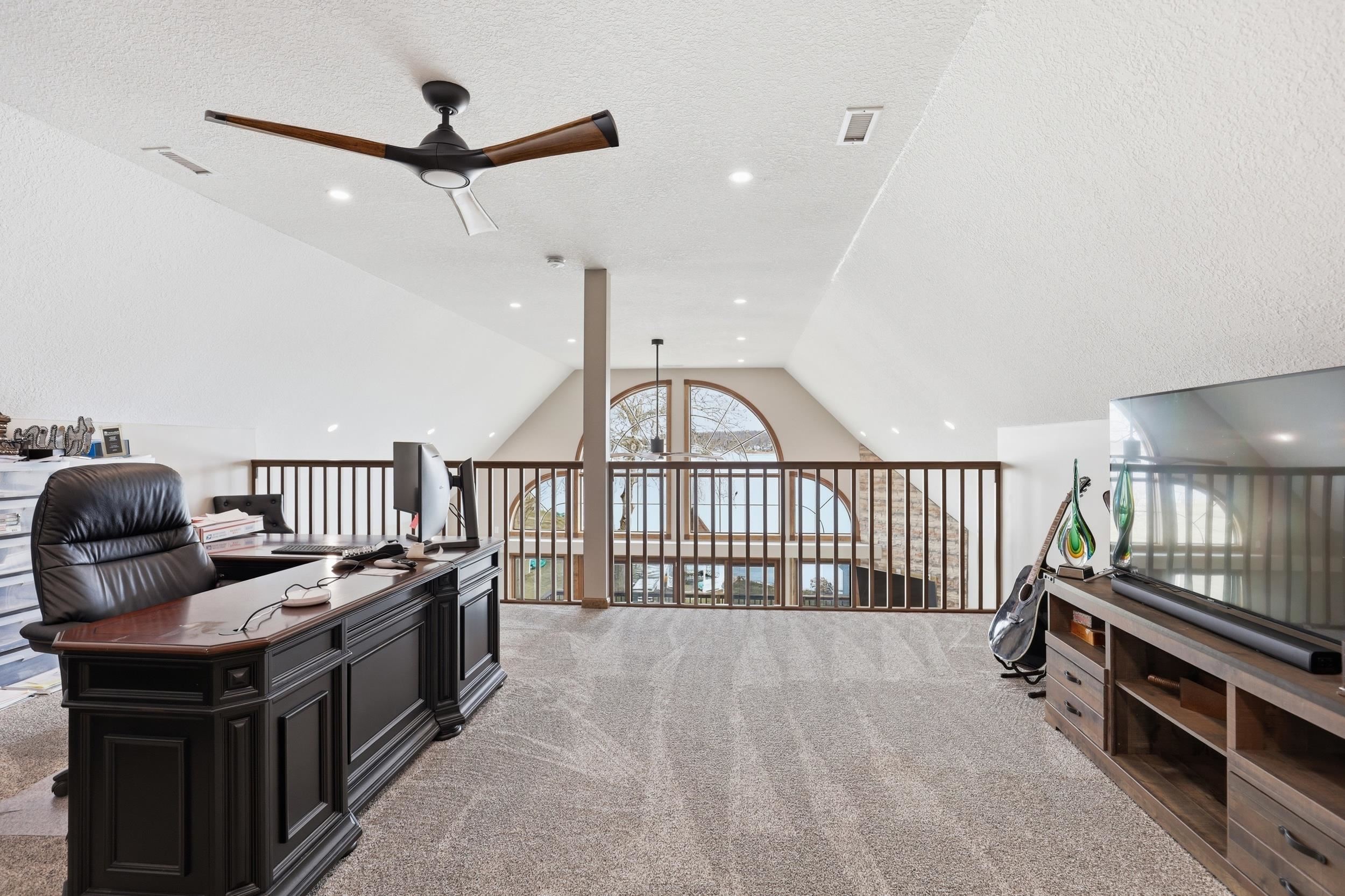 Home office featuring ceiling fan, light colored carpet, and a textured ceiling