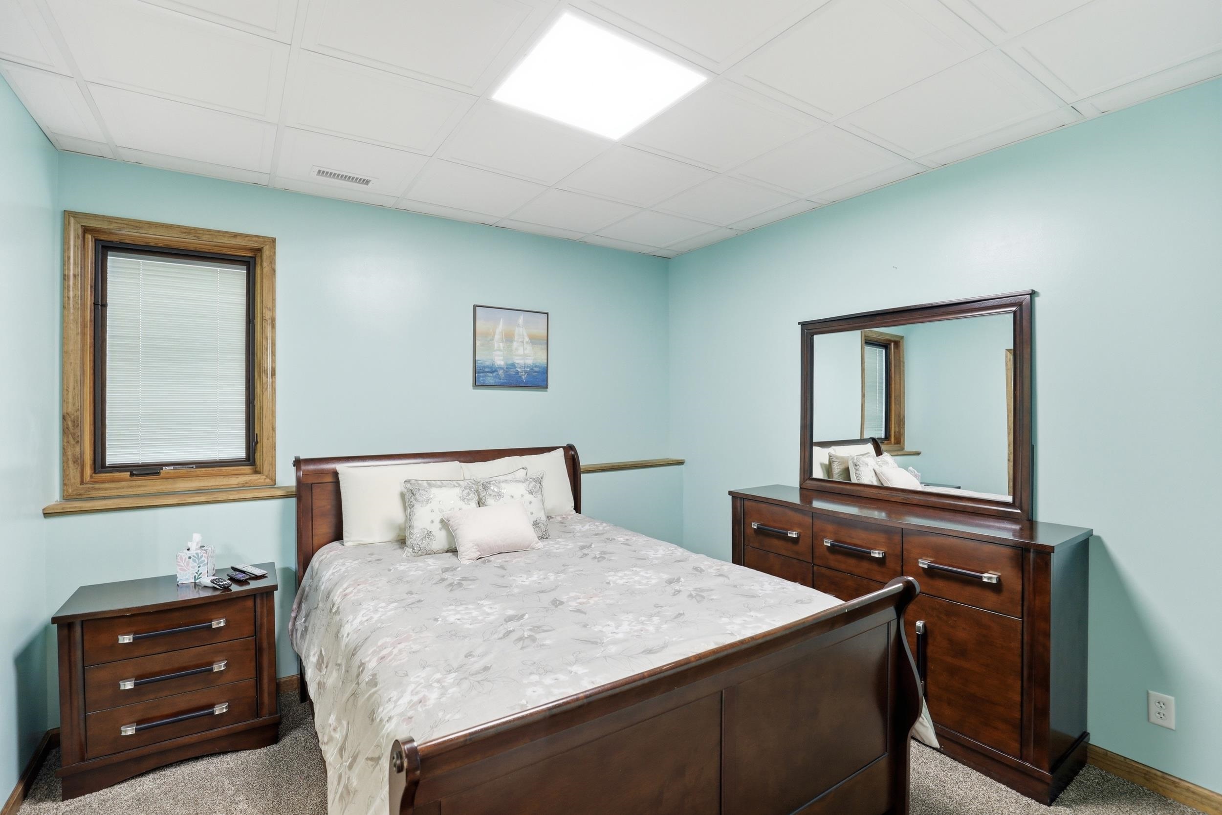 Bedroom featuring light colored carpet and a paneled ceiling