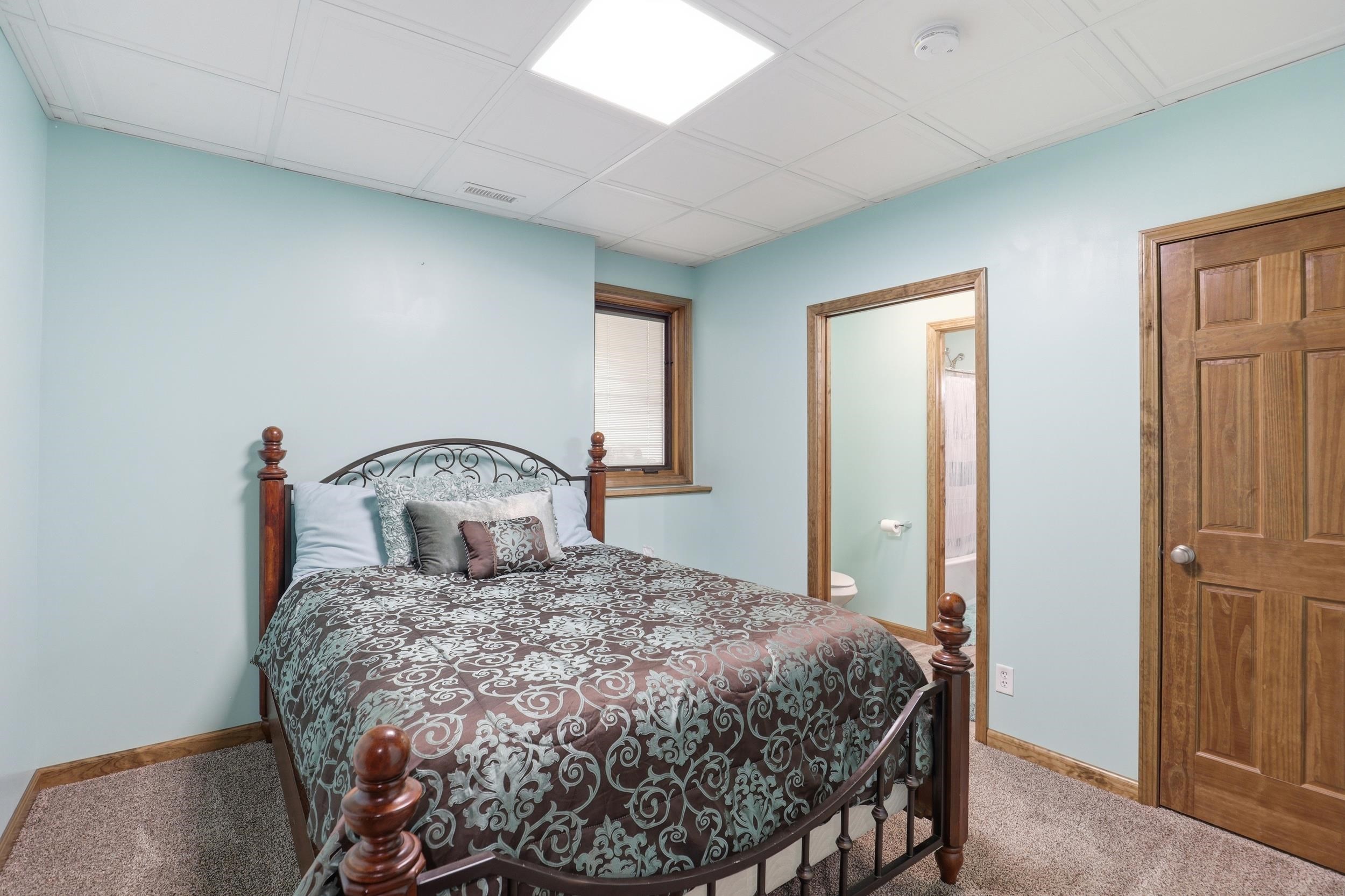 Carpeted bedroom featuring connected bathroom and a paneled ceiling