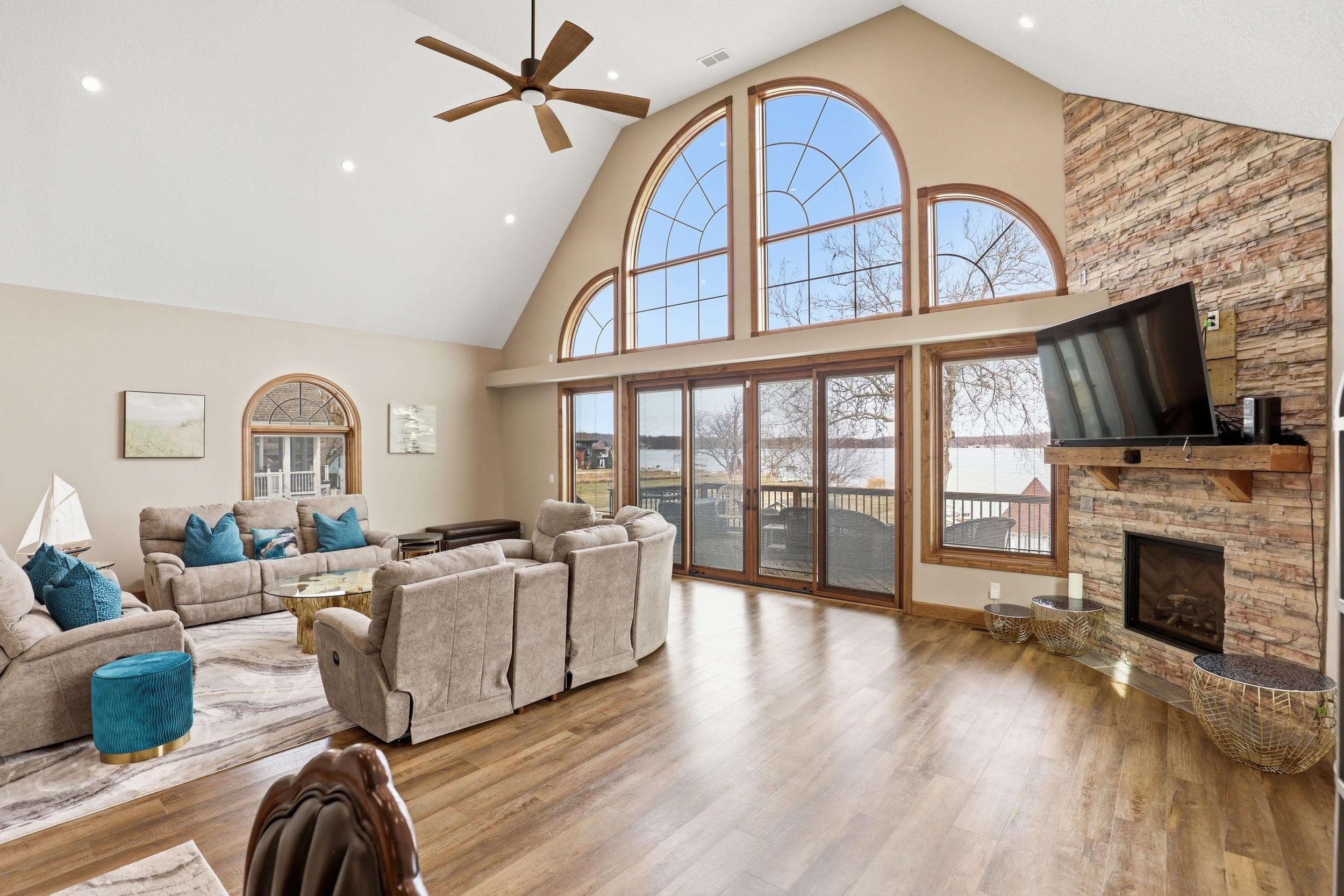 Living room with a ceiling fan, light wood-type flooring, a high ceiling, plenty of natural light, and recessed lighting