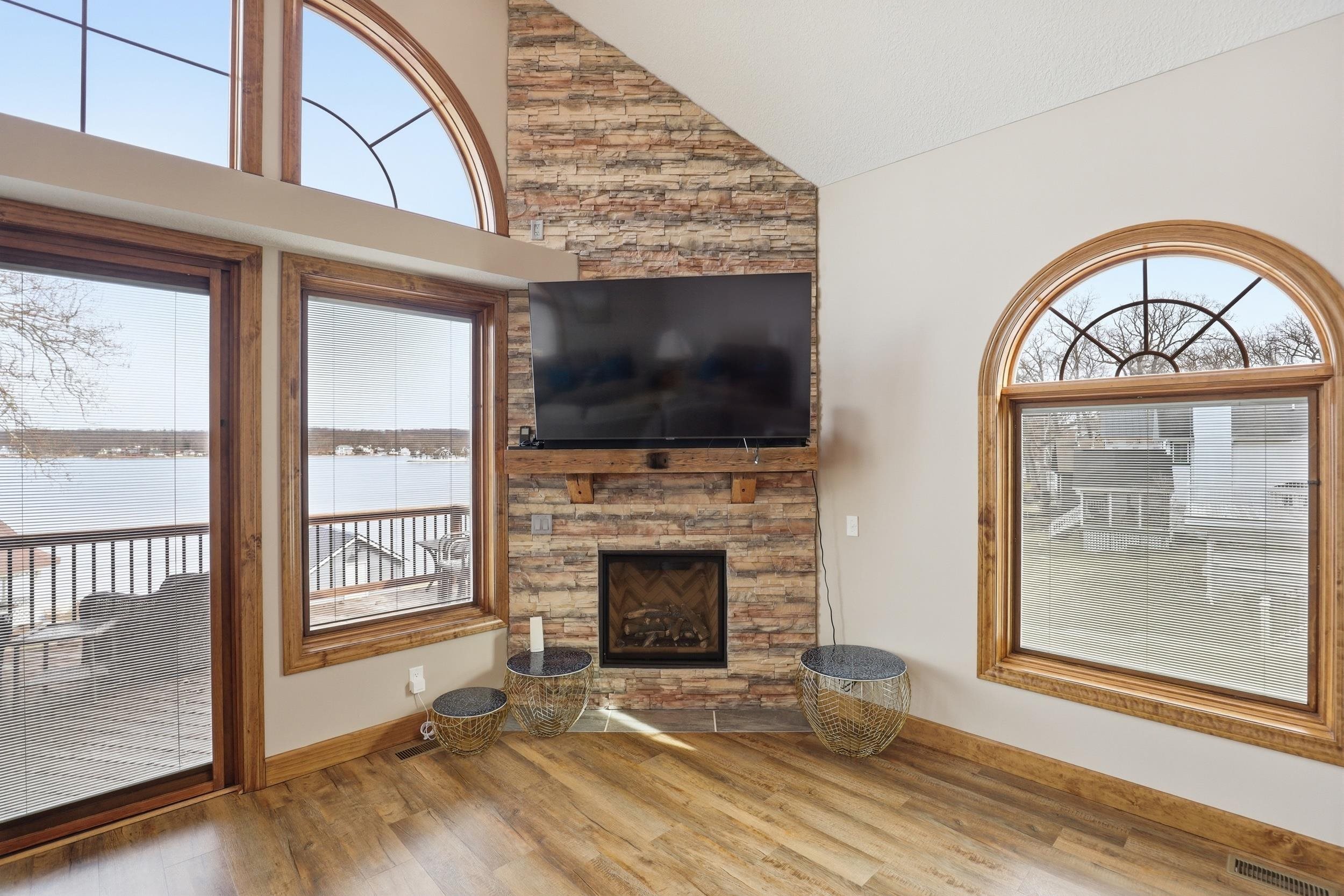 Unfurnished living room with light wood-style floors, a stone fireplace, and vaulted ceiling