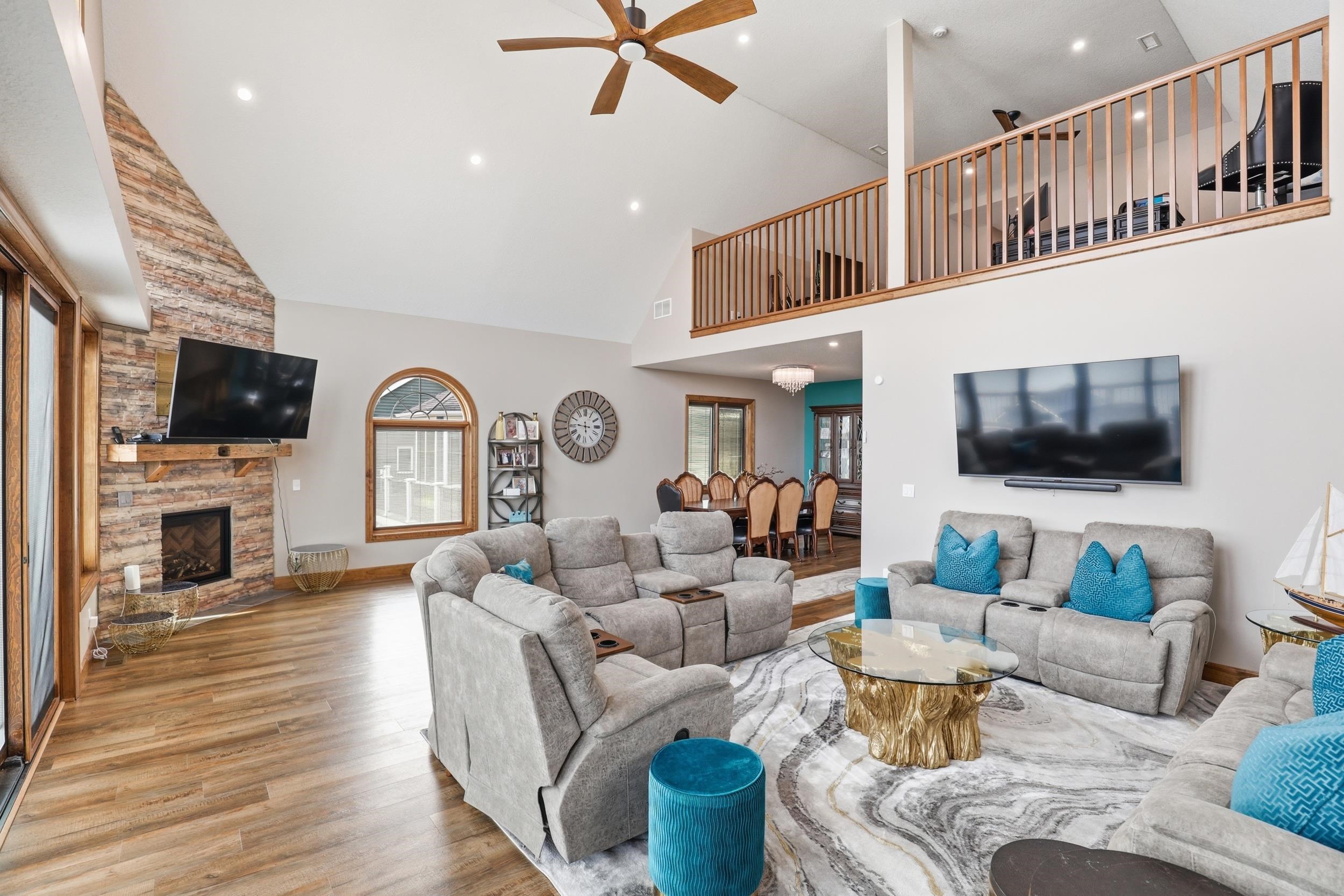 Living area featuring a ceiling fan, wood finished floors, a fireplace, vaulted ceiling, and recessed lighting