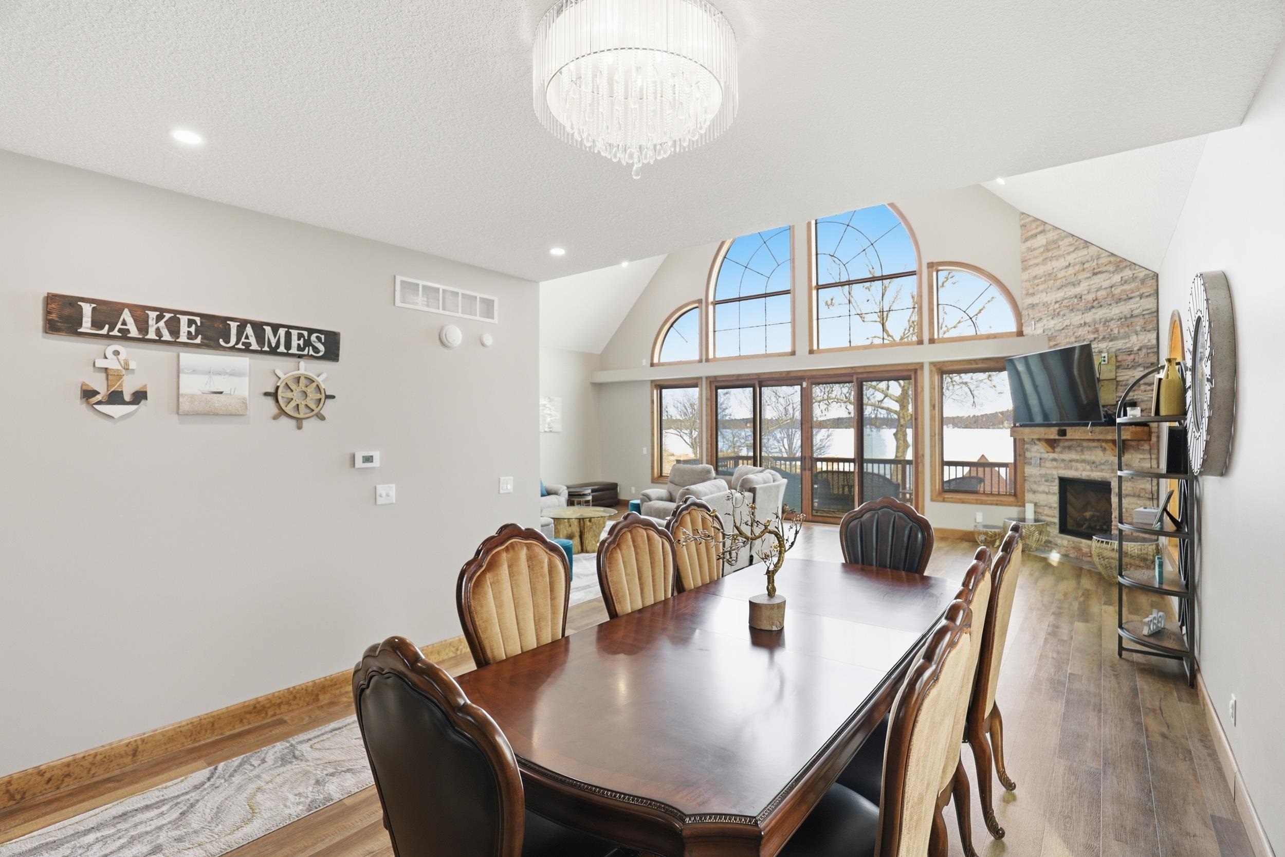 Dining space featuring wood finished floors, a stone fireplace, vaulted ceiling, and a chandelier