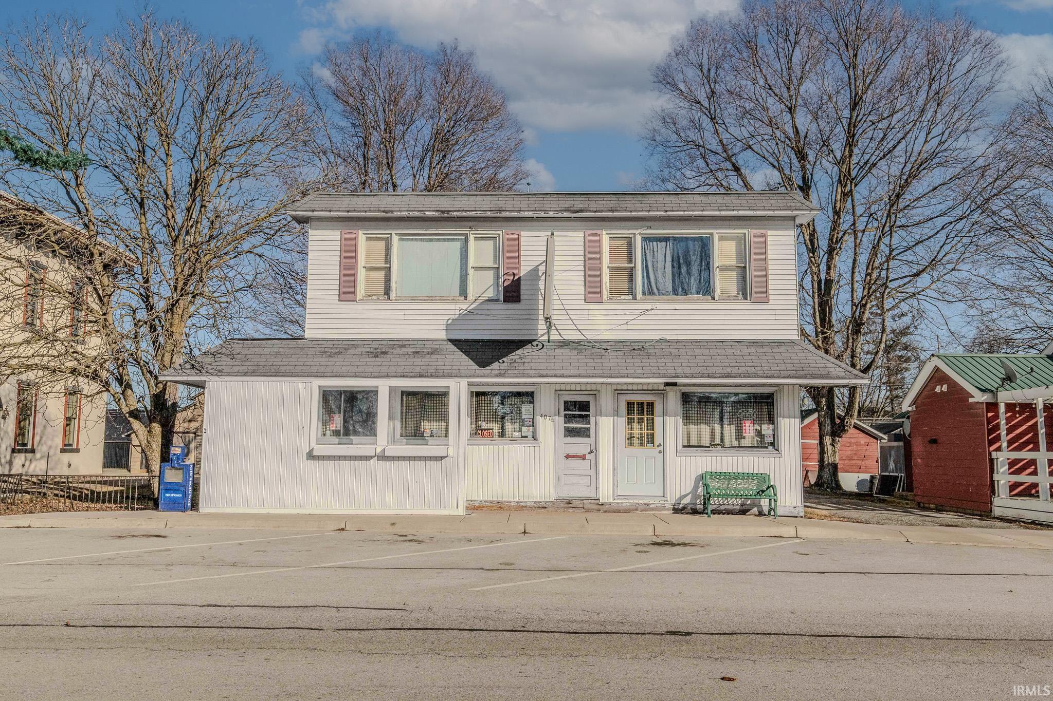Traditional-style home featuring uncovered parking, a shingled roof, and an outbuilding