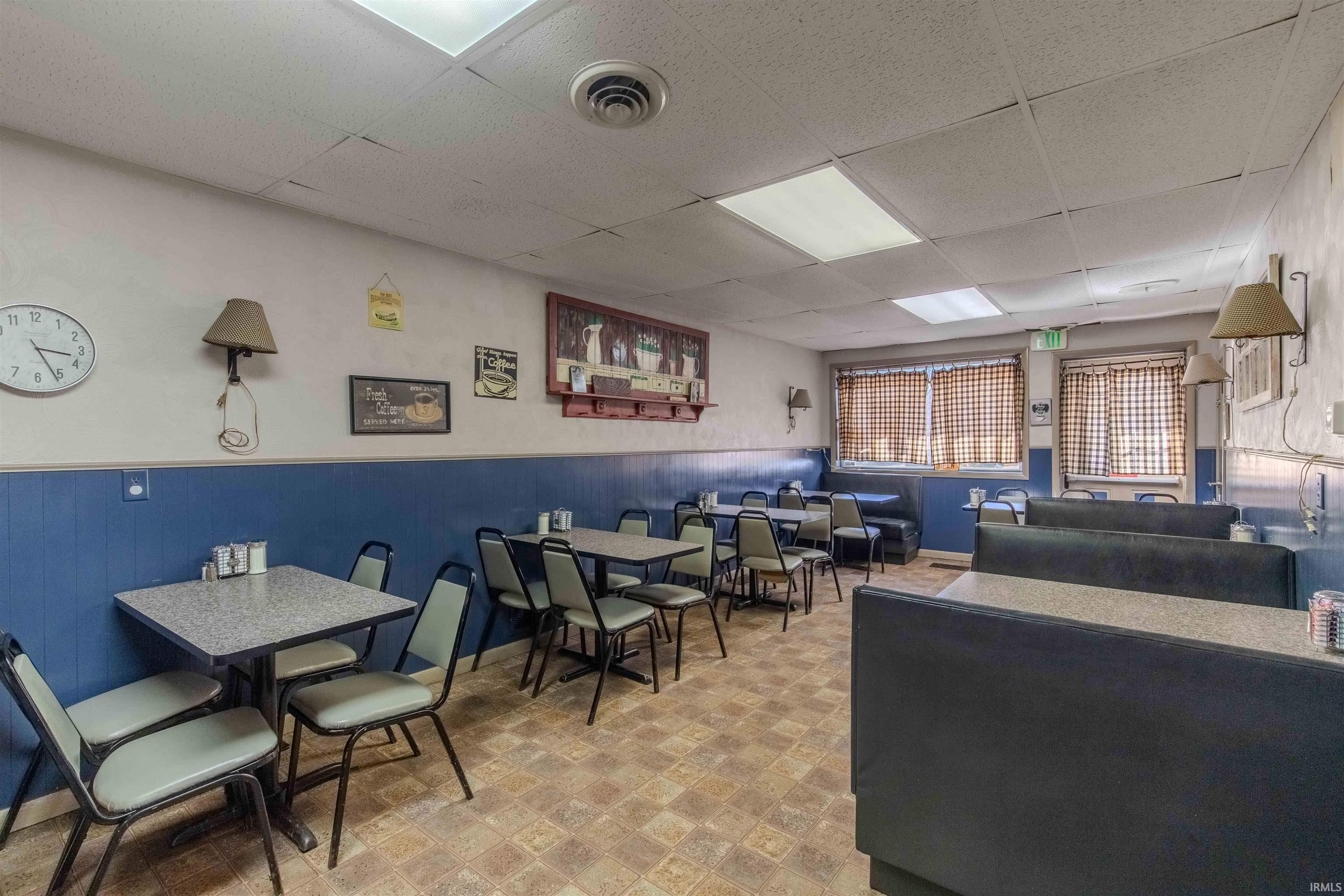 Dining space with a paneled ceiling, light flooring, and a wainscoted wall