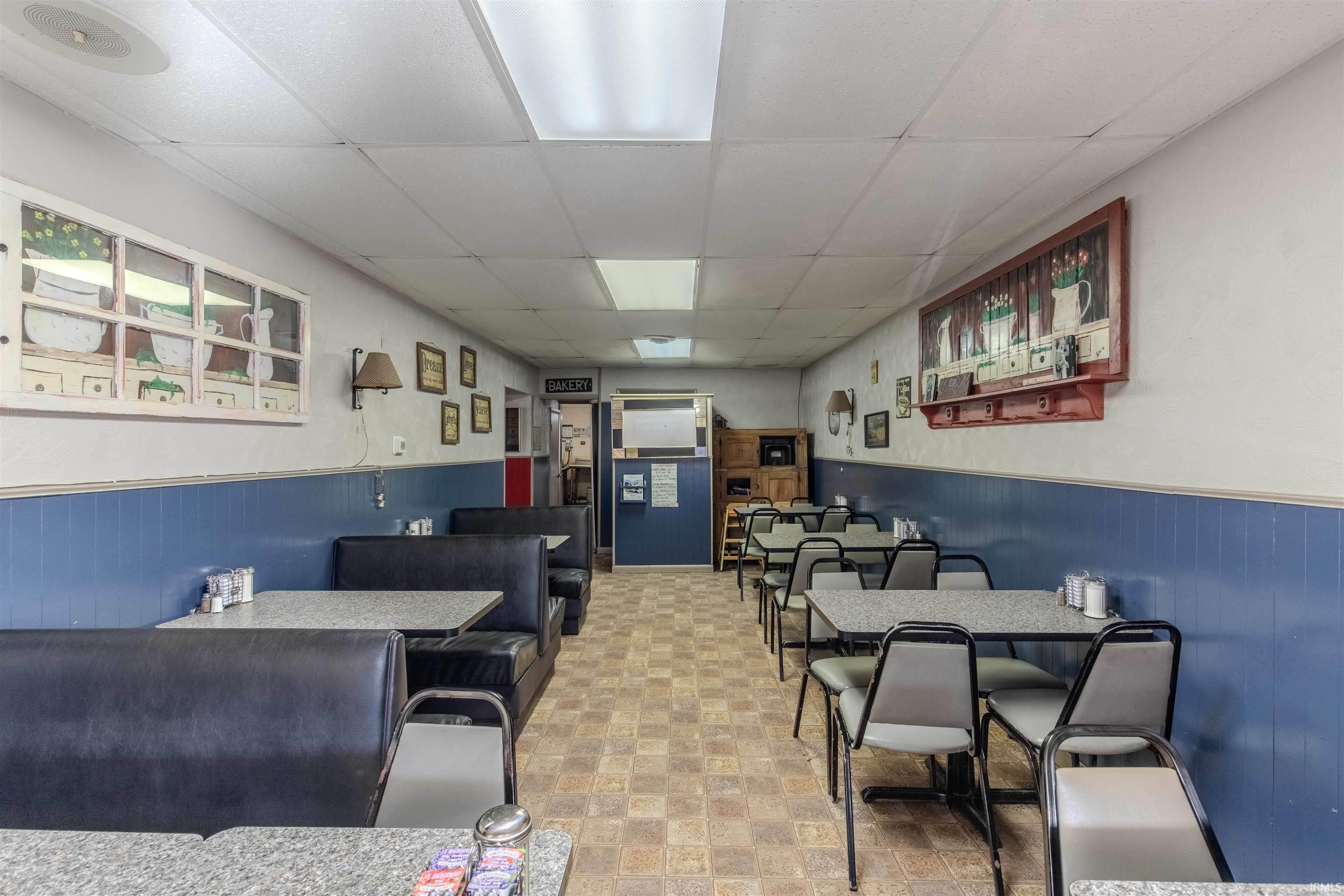 Dining space with a drop ceiling, a wainscoted wall, and wooden walls