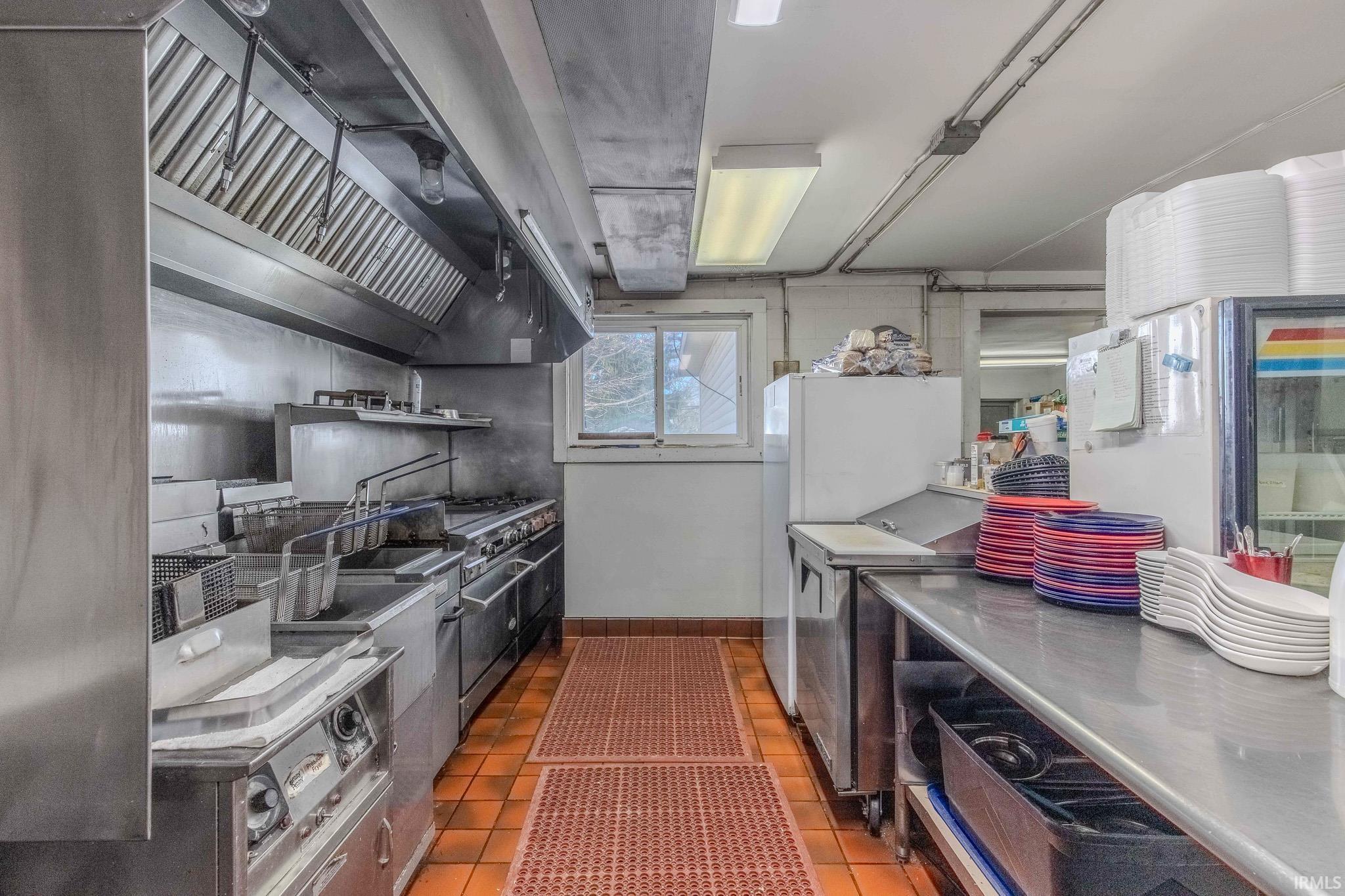 Kitchen with stainless steel countertops, freestanding refrigerator, open shelves, and range with two ovens