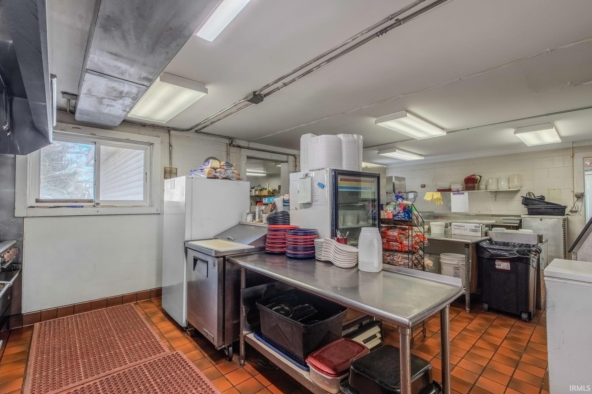 Kitchen featuring freestanding refrigerator, white refrigerator, stainless steel refrigerator, and exhaust hood