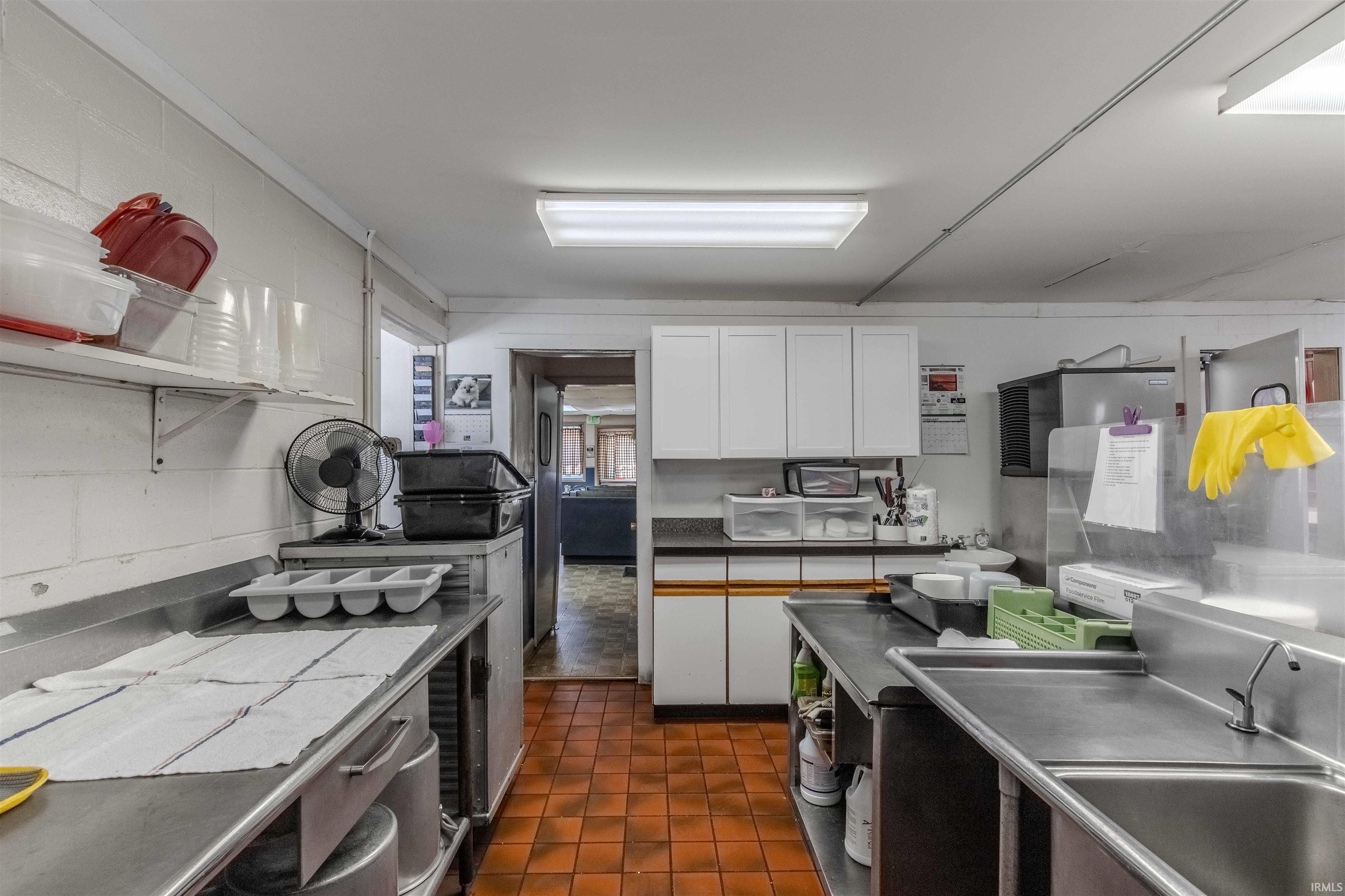 Kitchen featuring white cabinets, stainless steel counters, and open shelves