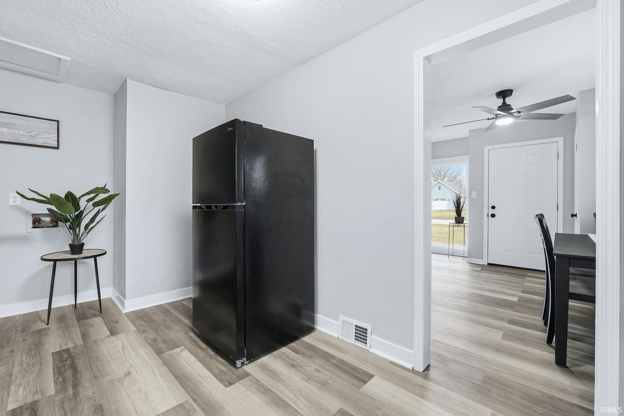 Kitchen with freestanding refrigerator, light wood-style flooring, a ceiling fan, and a textured ceiling