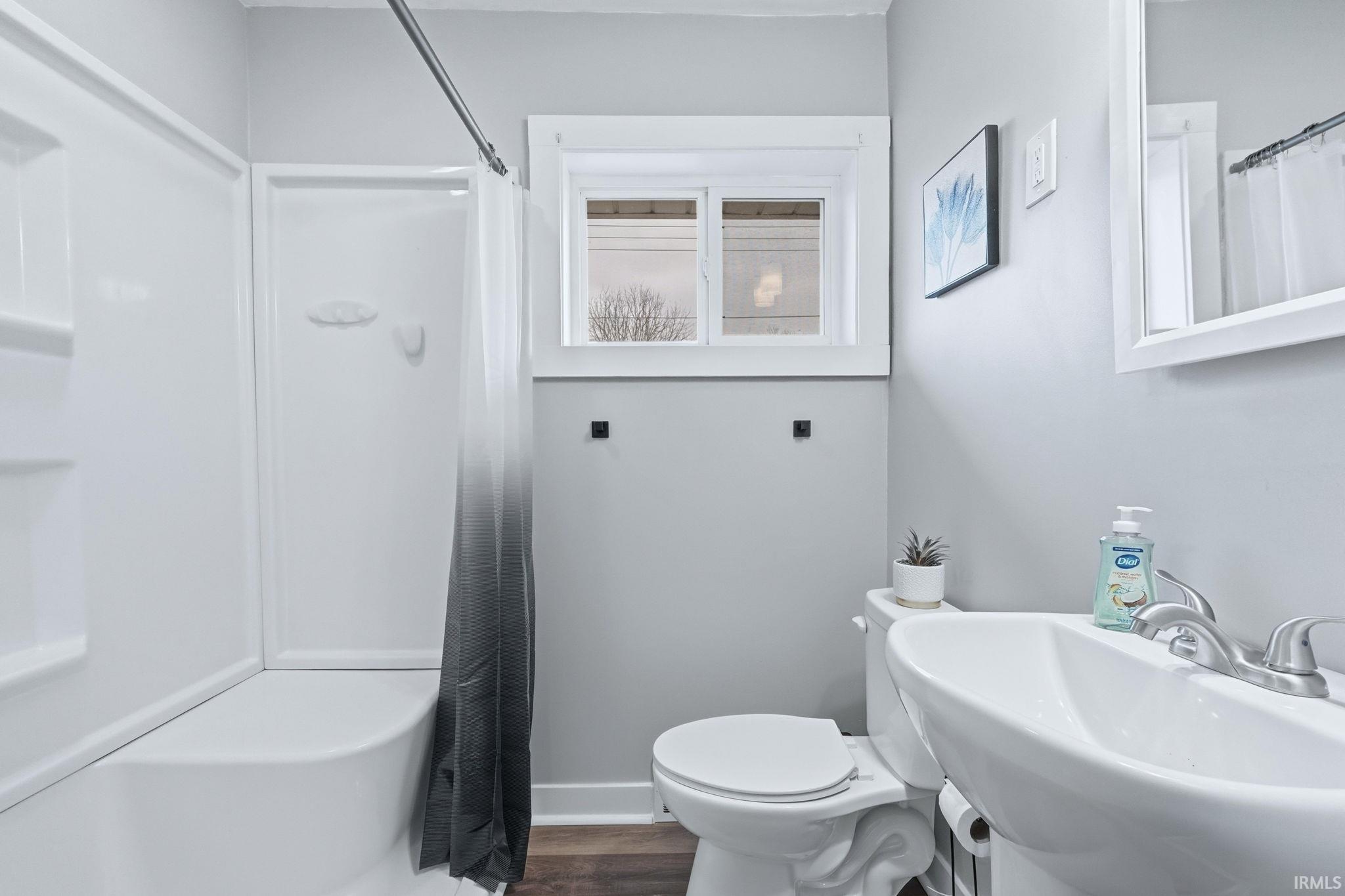 Bathroom with a shower with curtain and dark wood-style floors