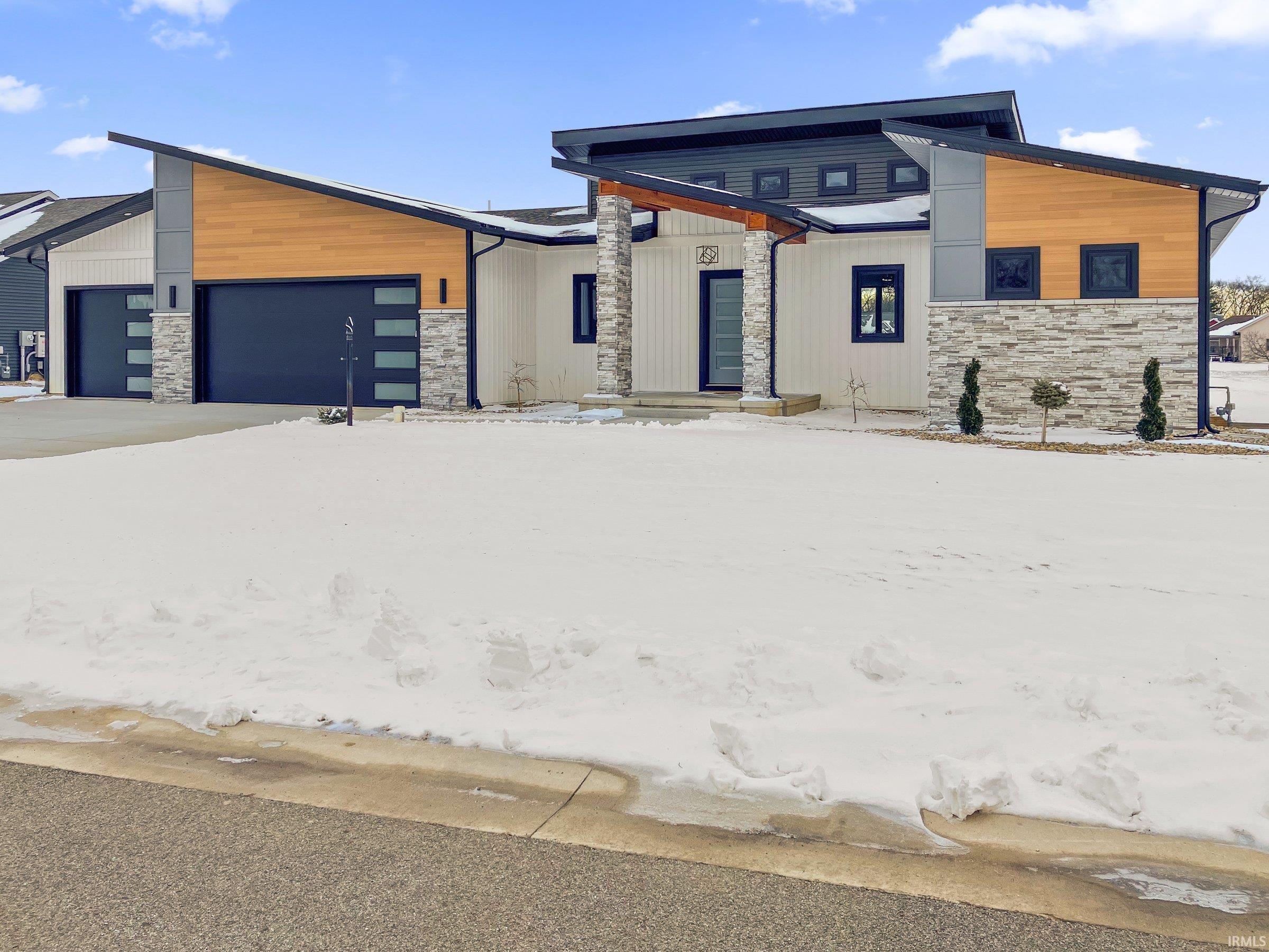 Modern home with stone siding and a garage