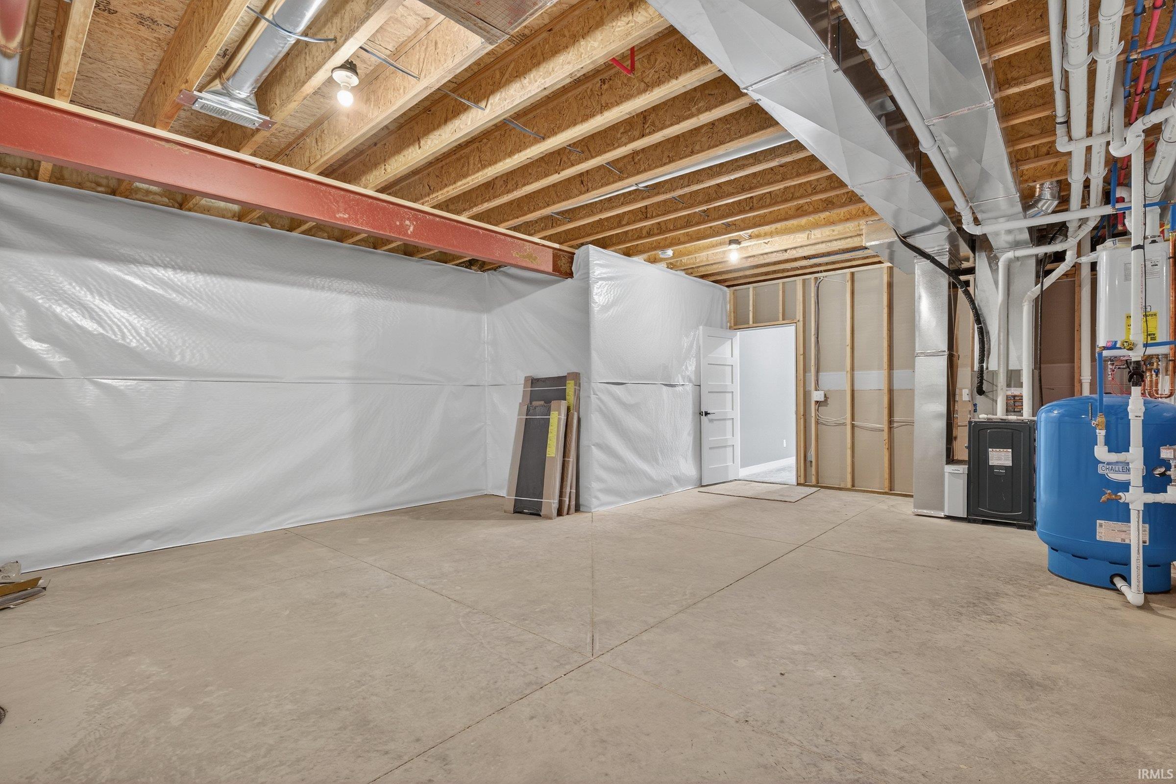 Unfinished below grade area featuring a water pressure tank and heating unit