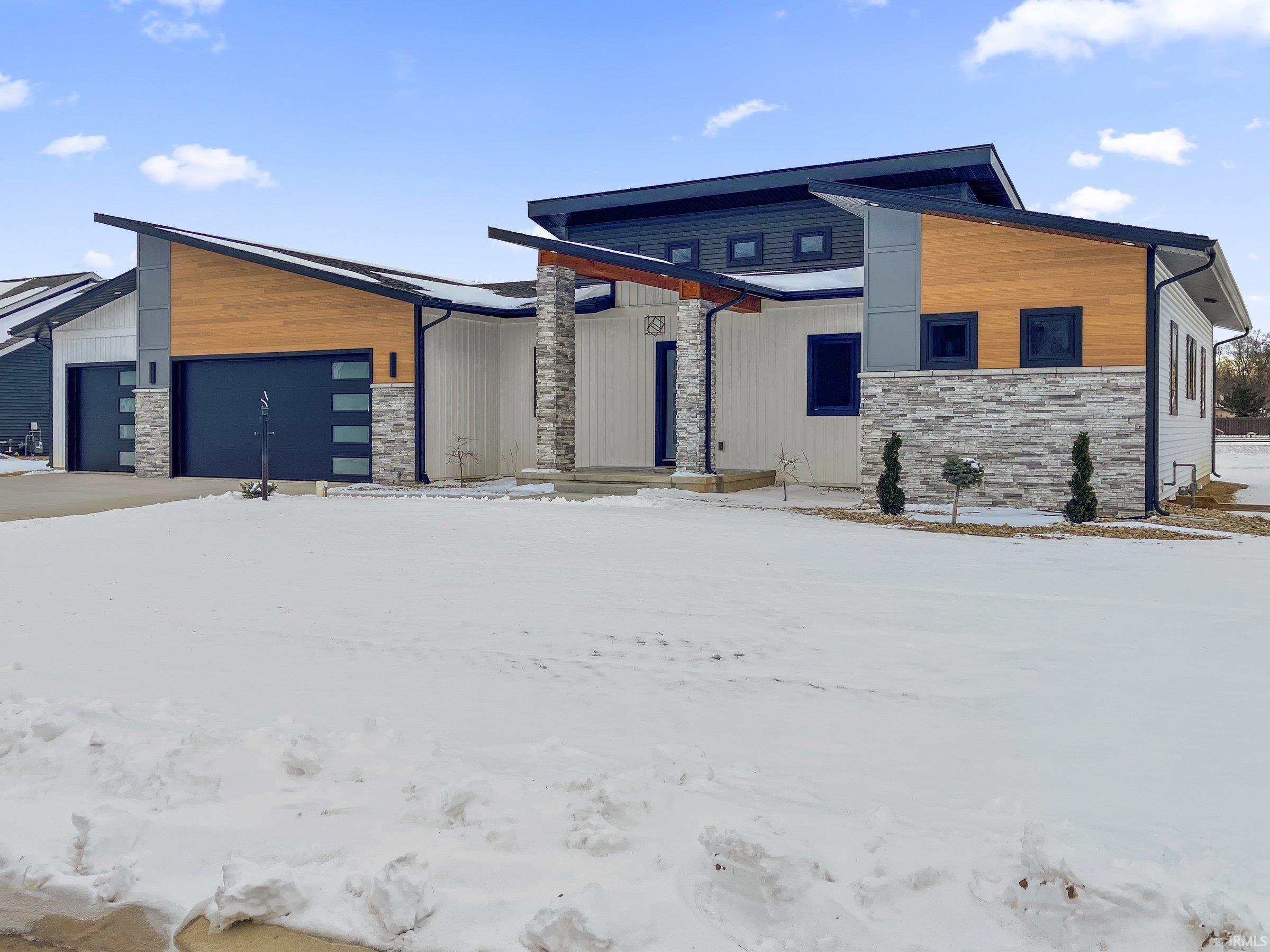 Modern home with stone siding and an attached garage