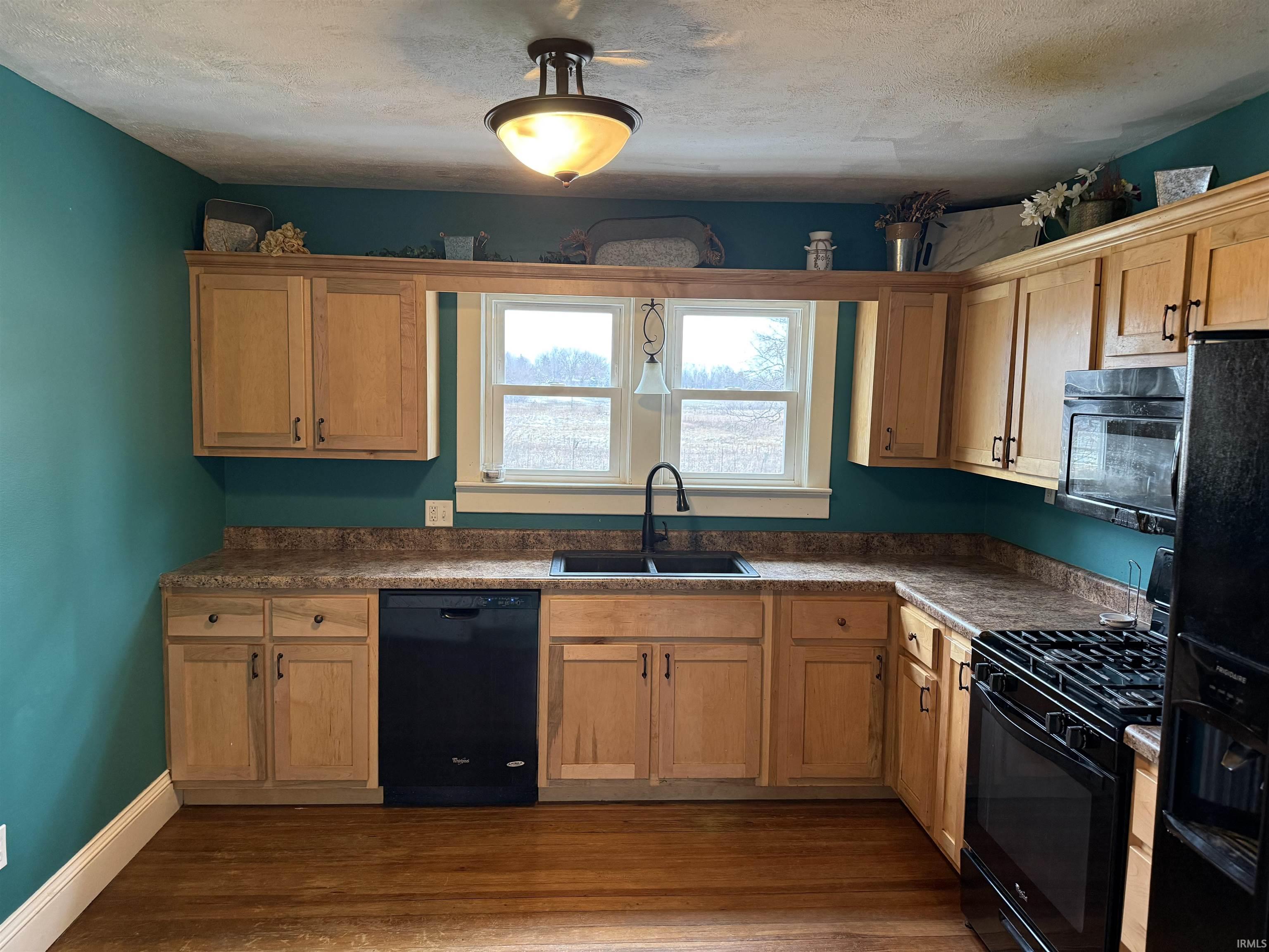 Kitchen featuring black appliances, dark wood-style floors, dark countertops, and a textured ceiling