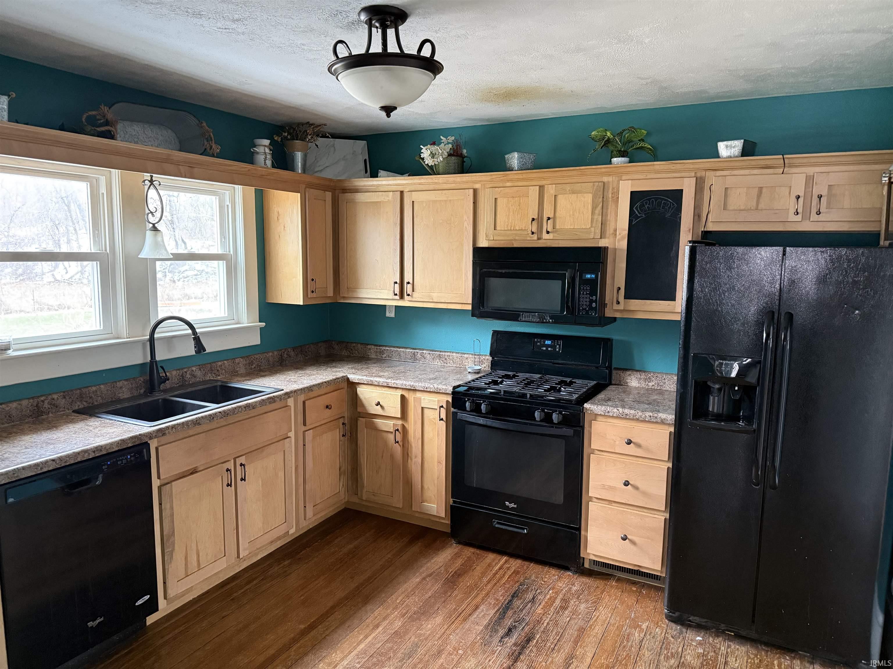 Kitchen featuring black appliances, dark wood-style floors, light wood finish cabinetry, a textured ceiling, and light countertops
