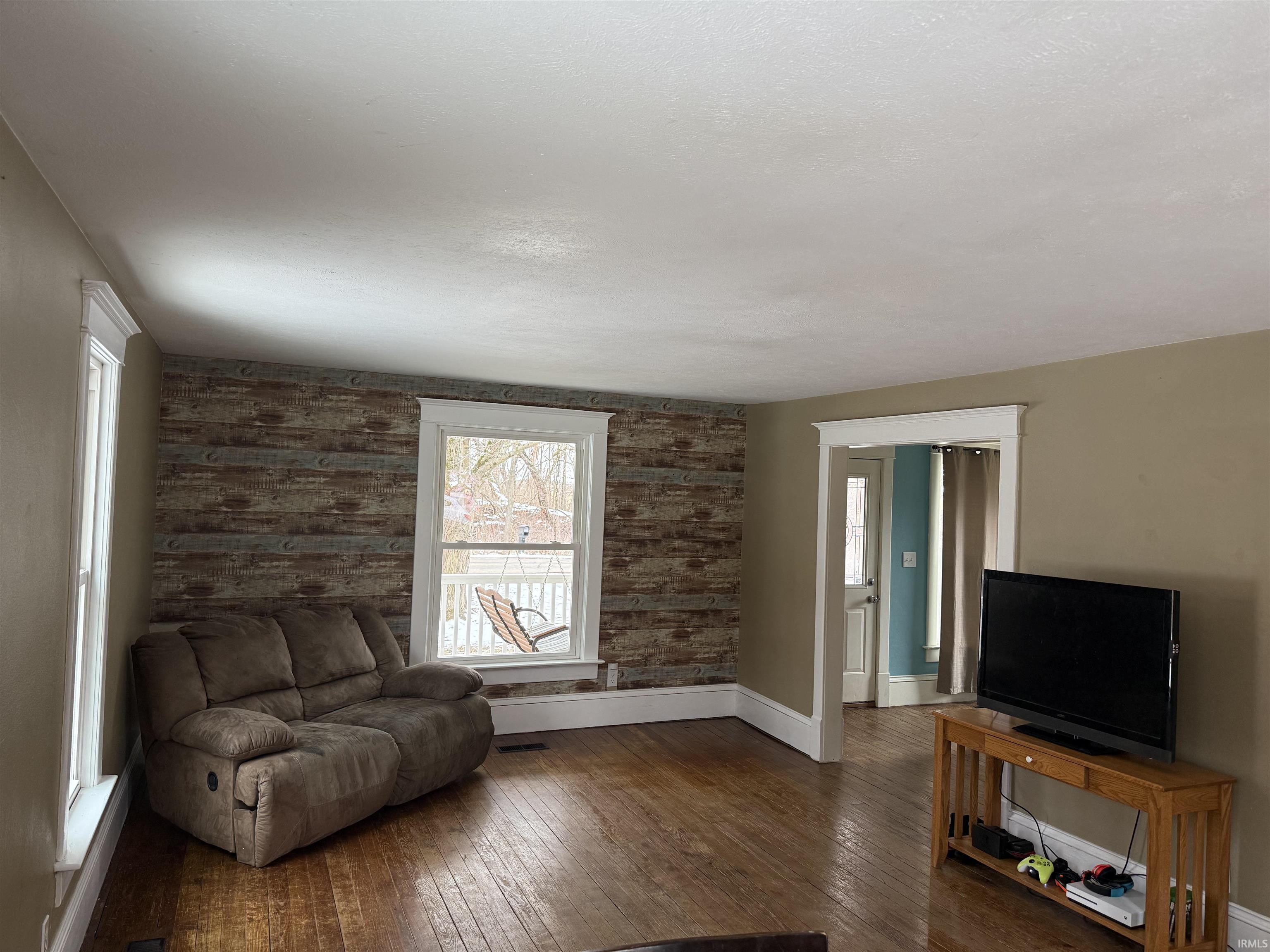 Sitting room featuring wooden walls, hardwood / wood-style flooring, and an accent wall