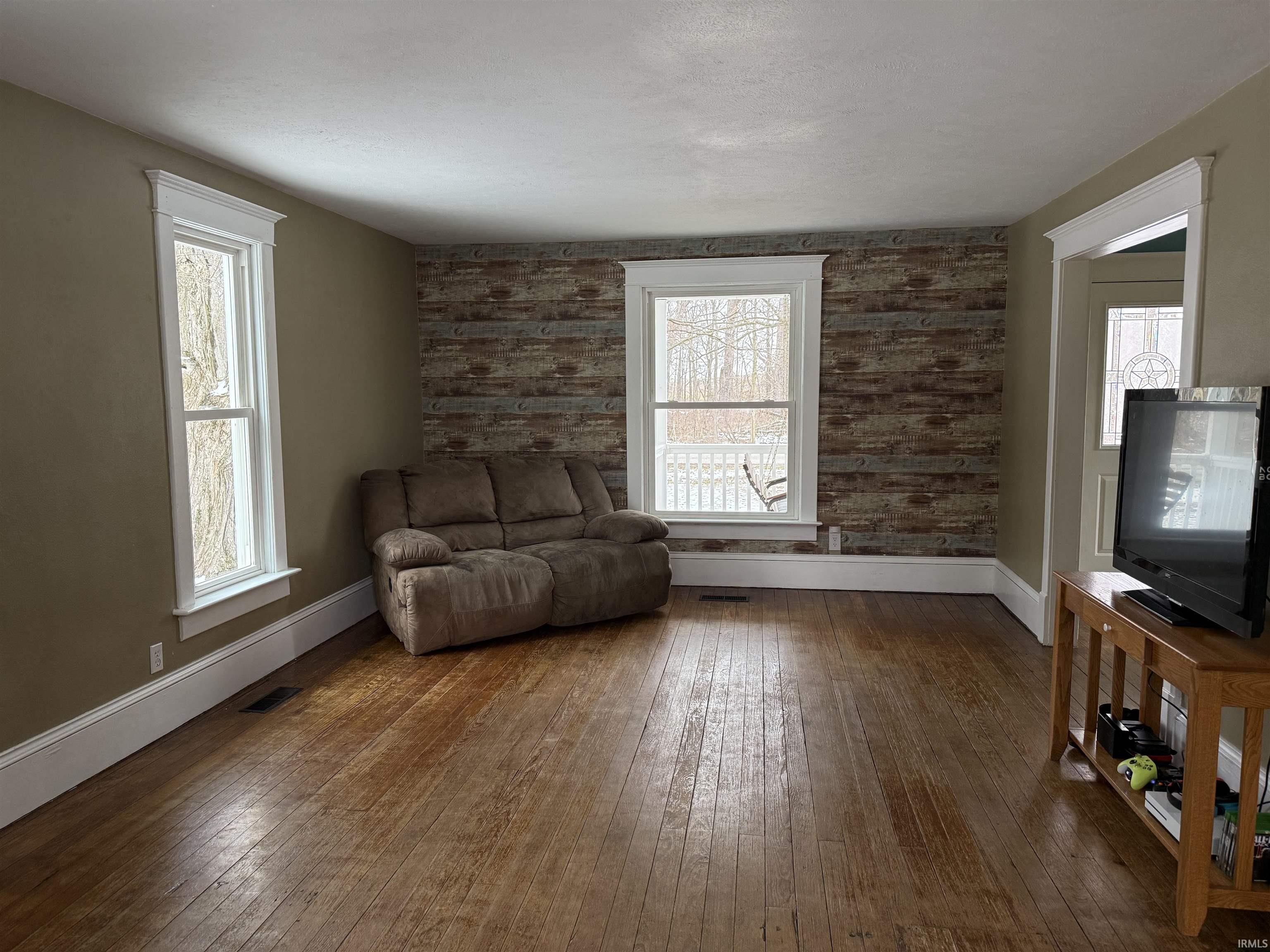 Living area with dark wood-style floors, an accent wall, and wood walls