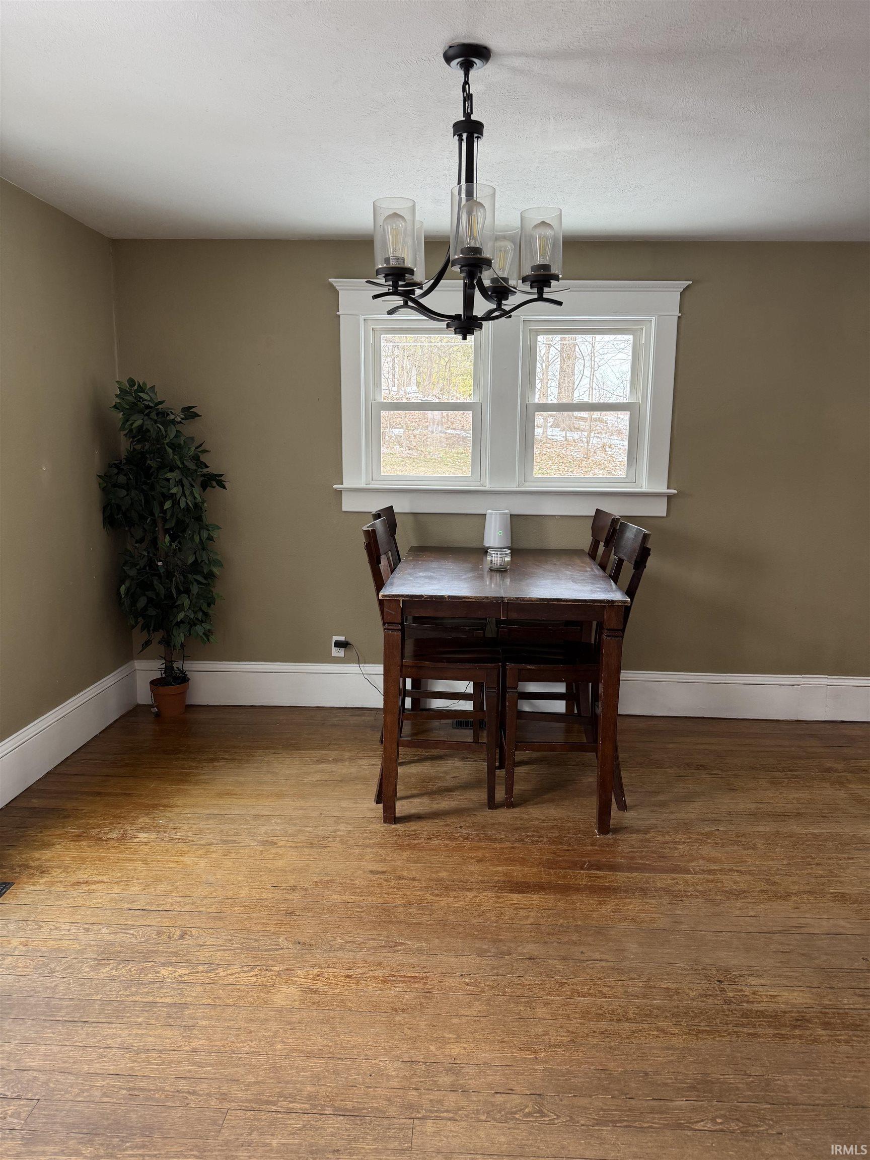 Dining room with light wood-style floors and suspended lighting