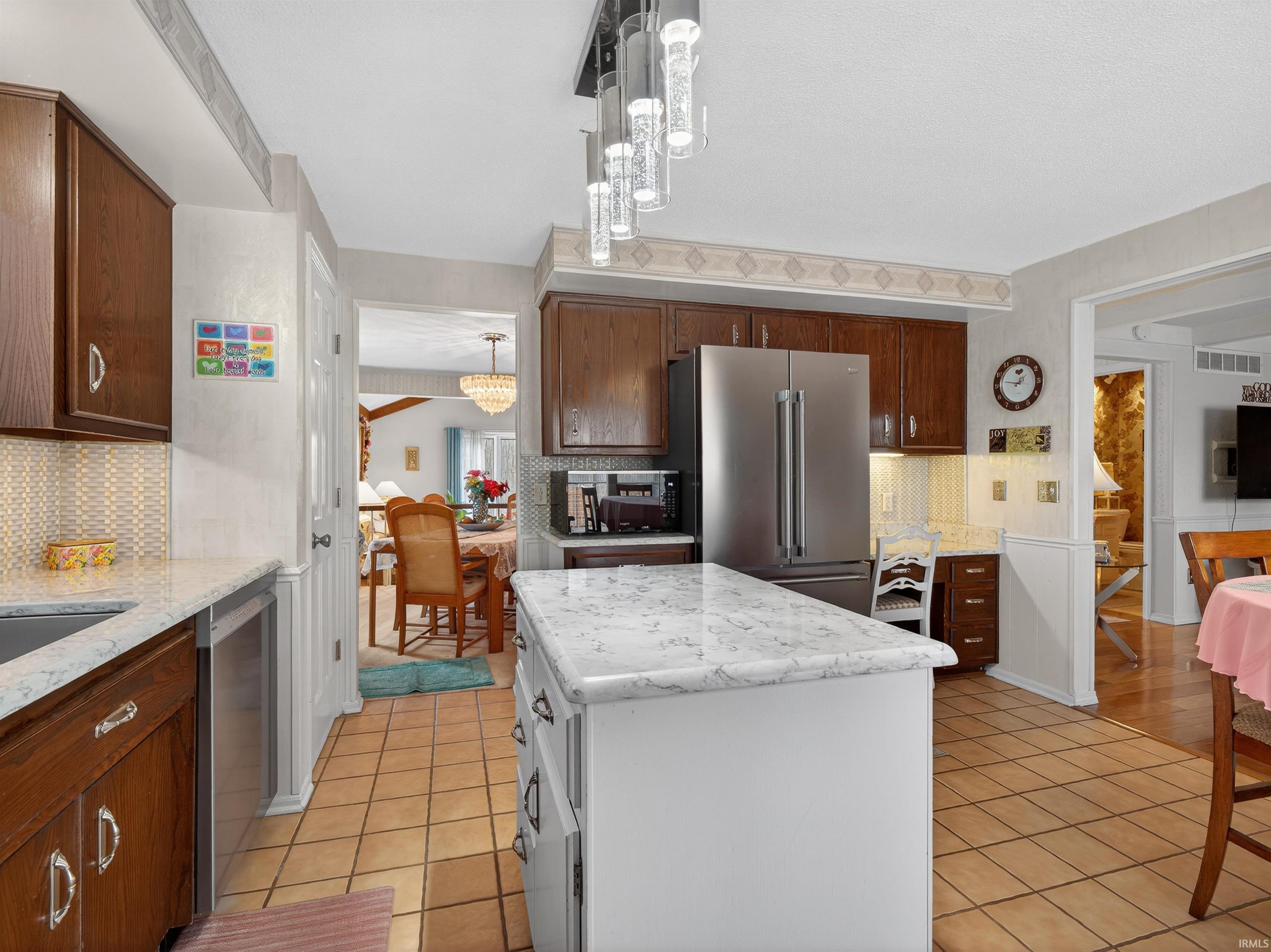 Kitchen featuring decorative backsplash, stainless steel appliances, a center island, and light tile patterned floors