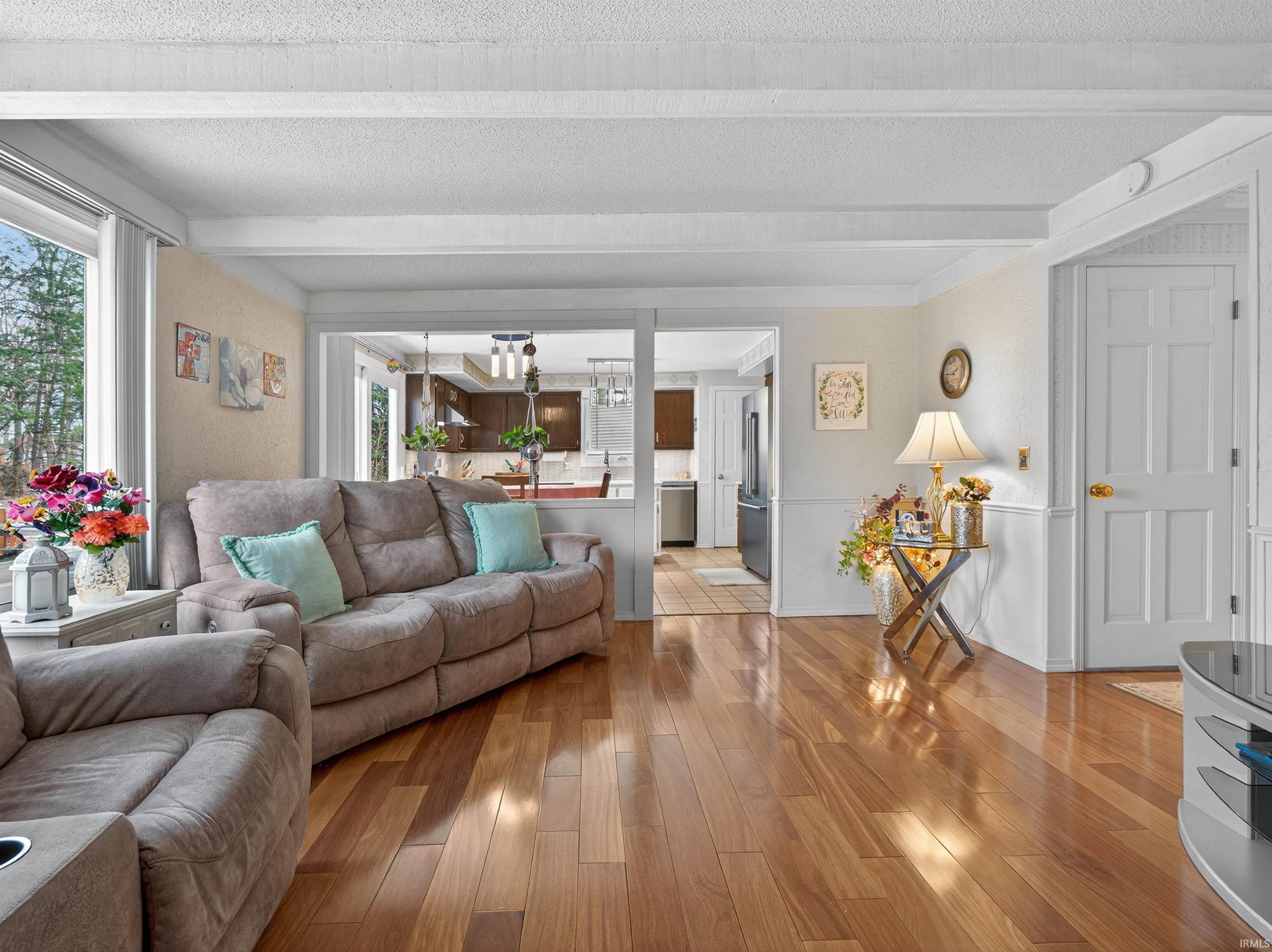 Living area with light wood-type flooring and beamed ceiling