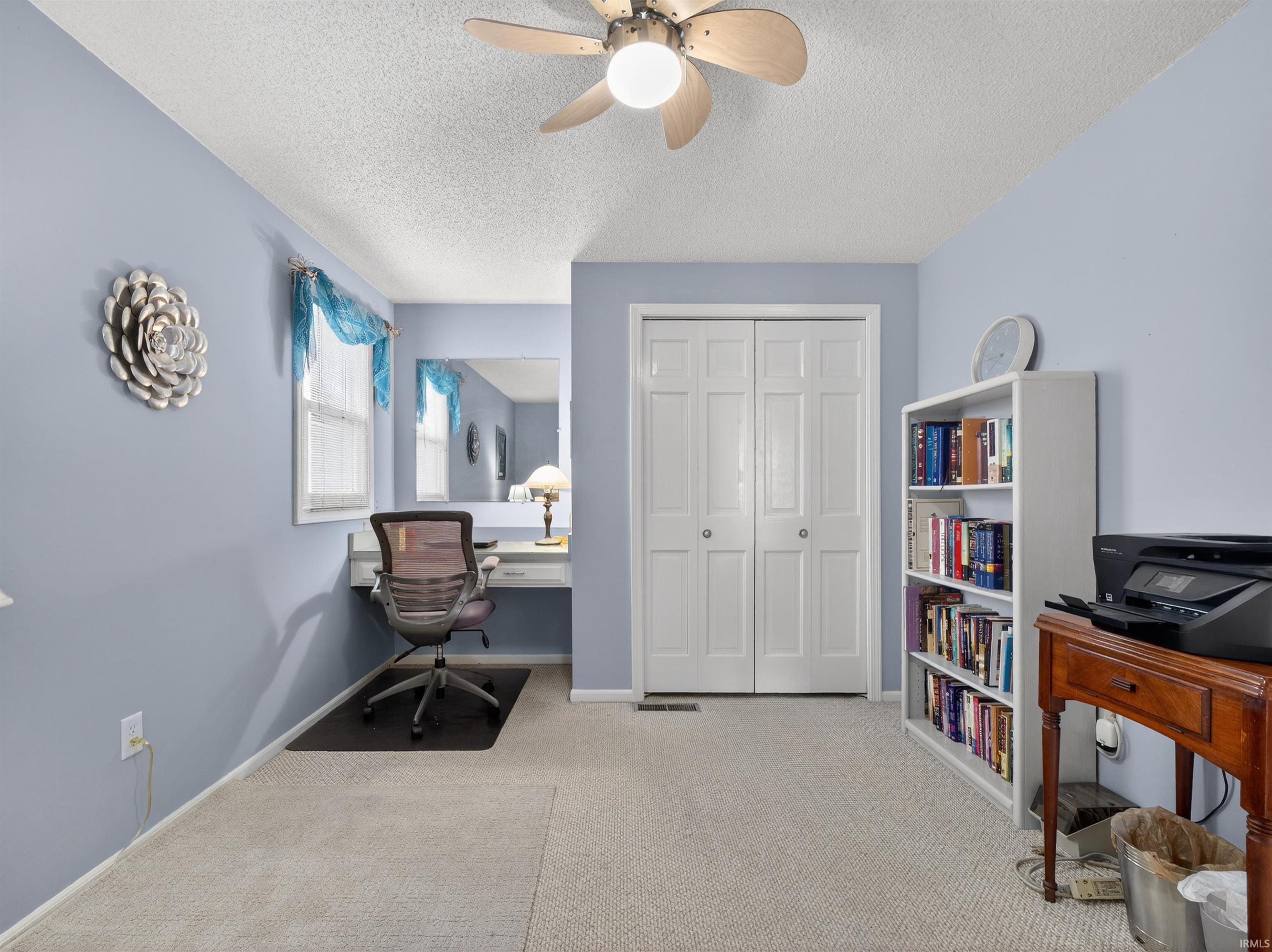 Home office featuring light colored carpet, a ceiling fan, and a textured ceiling